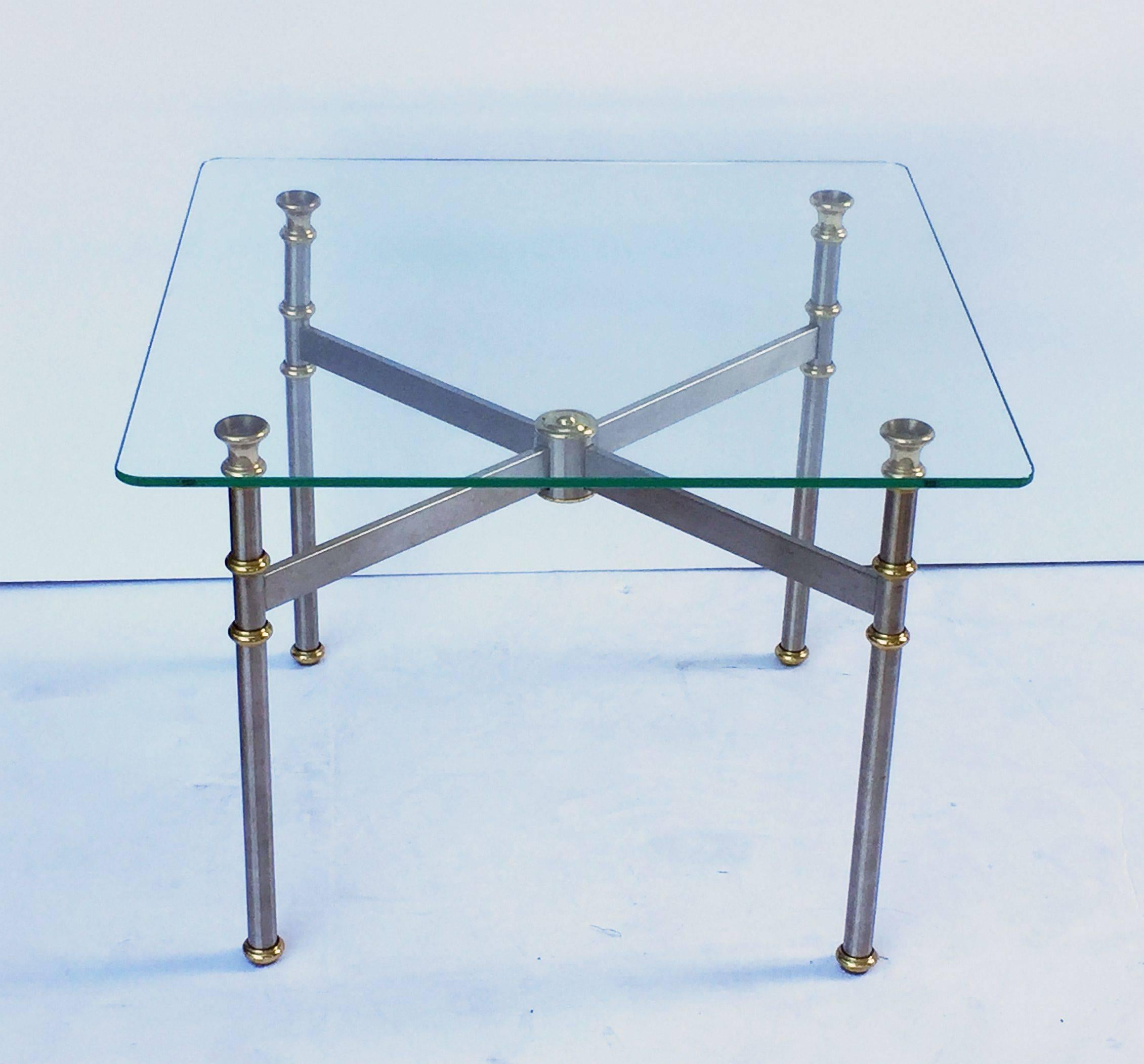 A fine French low coffee or cocktail table featuring a square clear glass top set upon a stylish base of brushed steel and brass.

Perfect for use as a cocktail or coffee table.