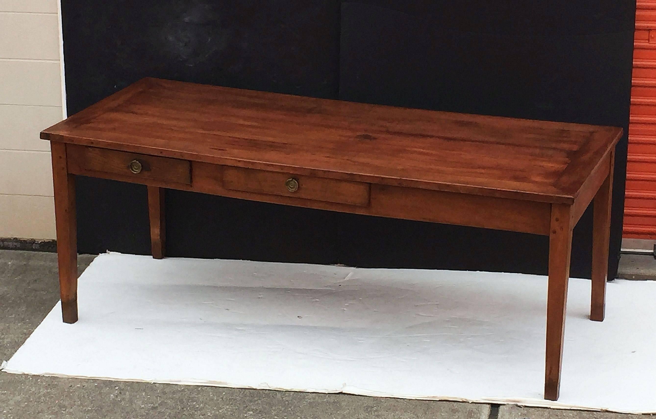 A handsome French farm table of cherry featuring a paneled rectangular top on a pegged frame with drawers on opposing sides (three drawers total, all with brass hardware), standing on square tapering legs. 

Makes a fine dining or breakfast table.