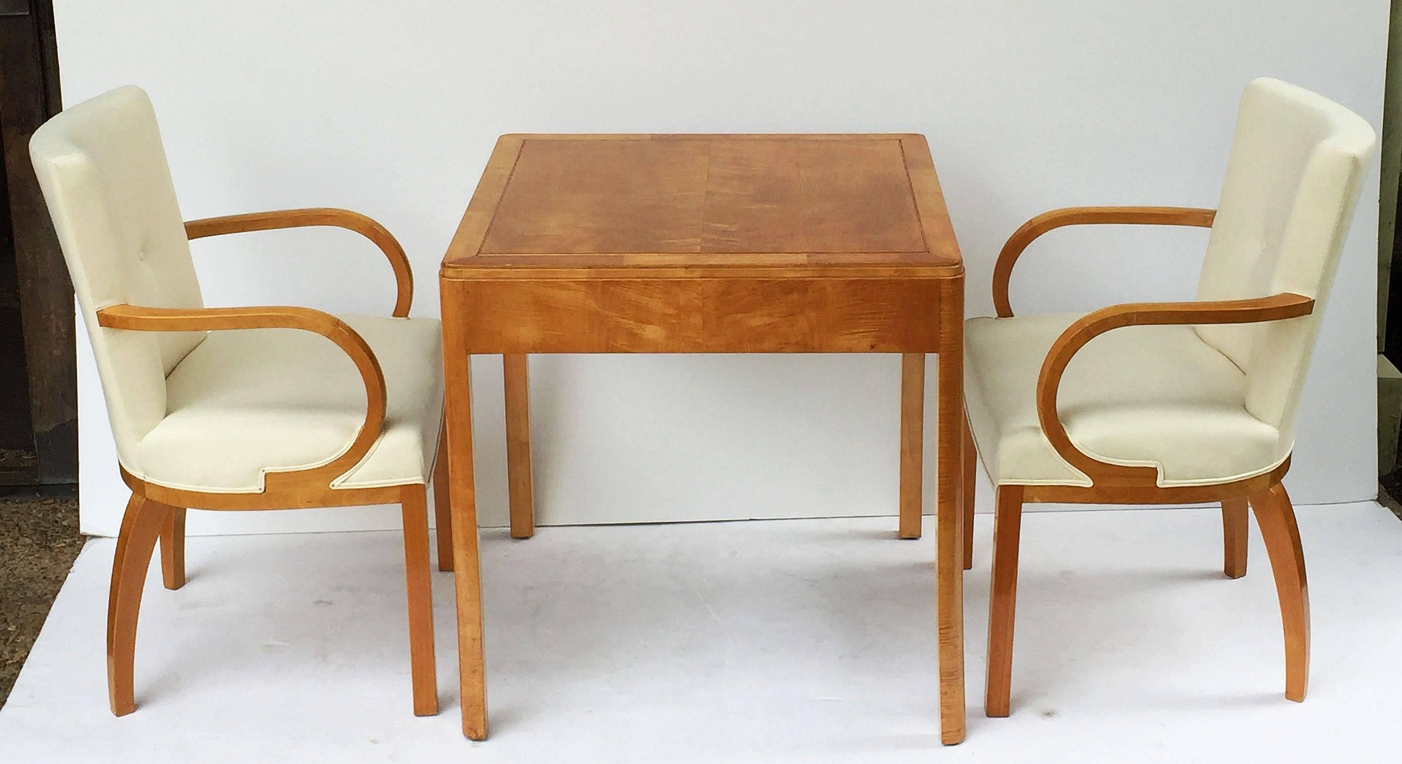 A stylish Danish table set with four comfortable upholstered armchairs of birch and a square table or game (card) table of birch with inset top featuring optional sides, one side showing flame-cut birch, the other side with embossed black leather