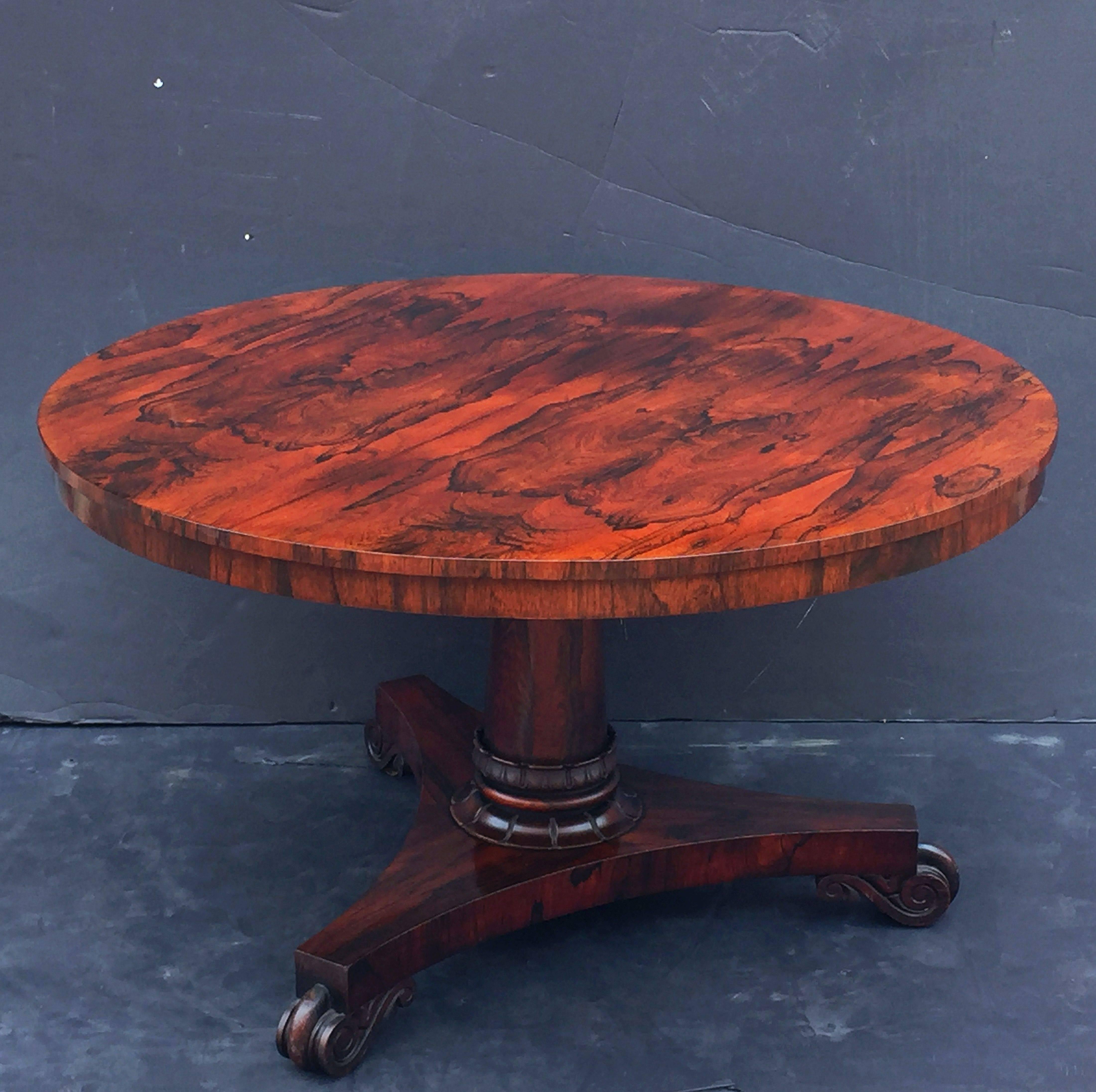 A fine English round centre table of rosewood from the William IV period, featuring a veneered top of figured rosewood.
Set upon a column pedestal and triform base, resting on scrolled feet, on rolling brass casters.
A Classic tilt-top with hinged