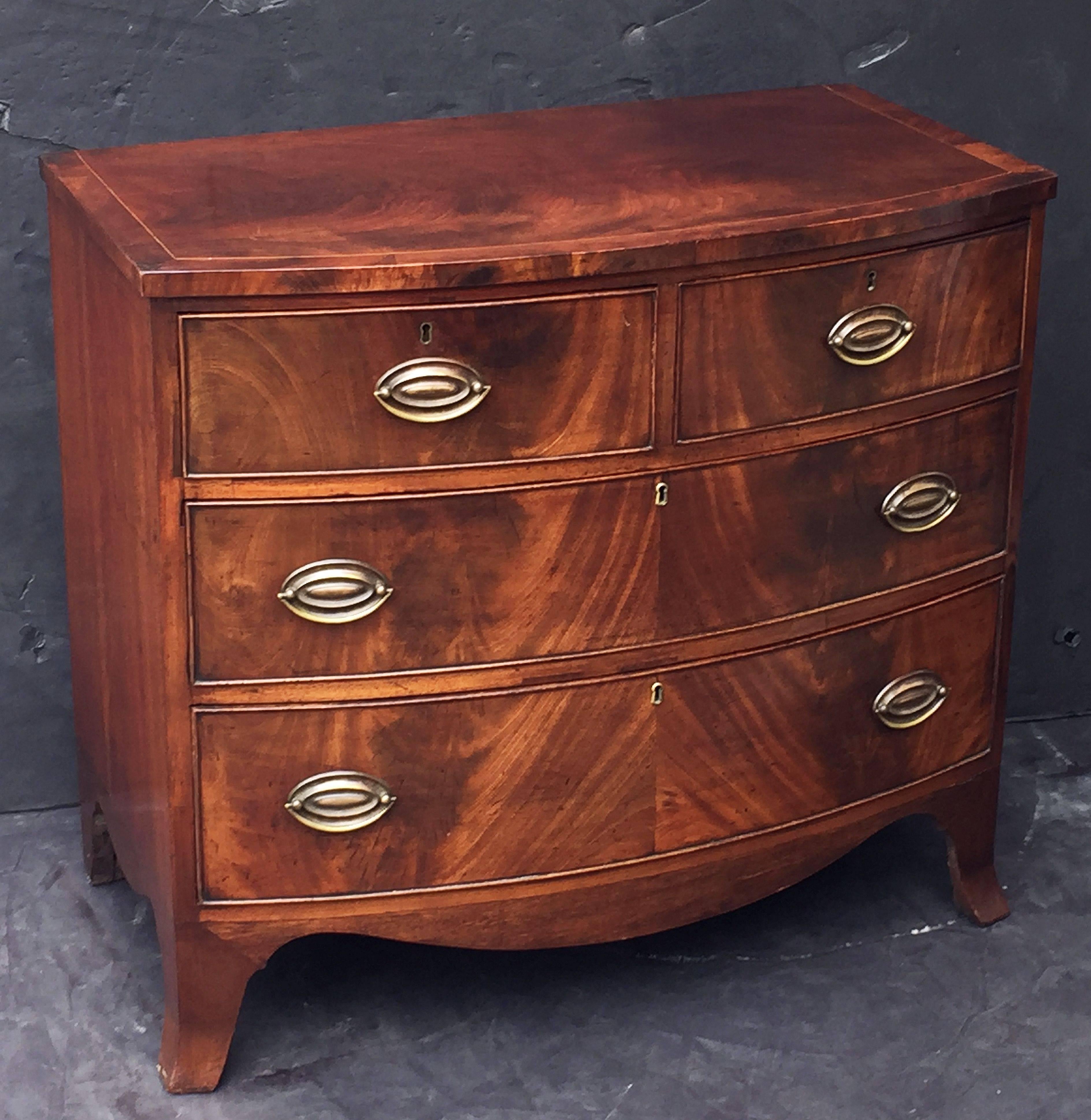 A handsome English bow-front chest of drawers of mahogany, featuring a bowed top over a frieze of two small beaded drawers and two beaded long drawers, with oval brass pulls, and set upon a serpentine splayed foot base.
The drawers showing
