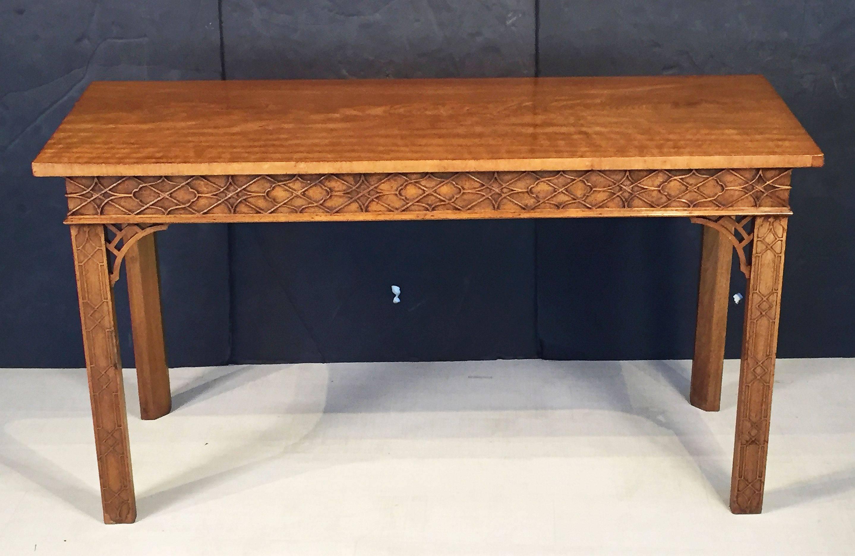 A fine English walnut console table or buffet server in the Chinese Chippendale style, featuring a figured walnut top over a carved fretwork frieze to the front and sides, on handsome carved canted supports, each leg with carved fretwork at the