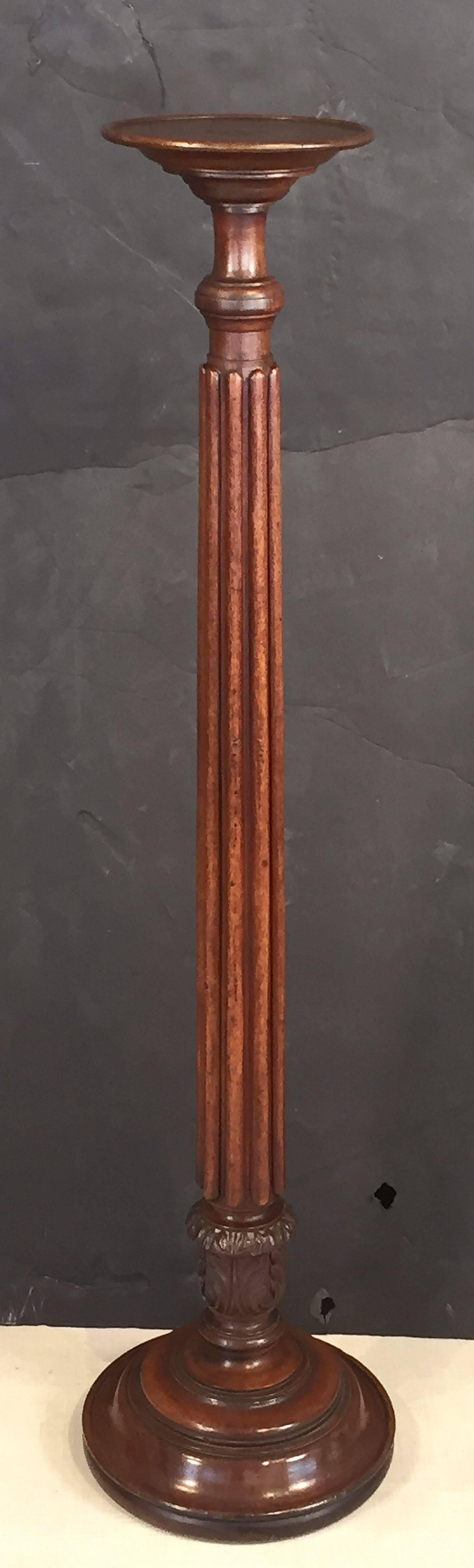 A fine English torchère (torchière) or column pedestal stand of mahogany - in the William IV style - featuring a moulded round top for candles or plants, turned column support, and raised round pedestal base with carved acanthus leaves design.