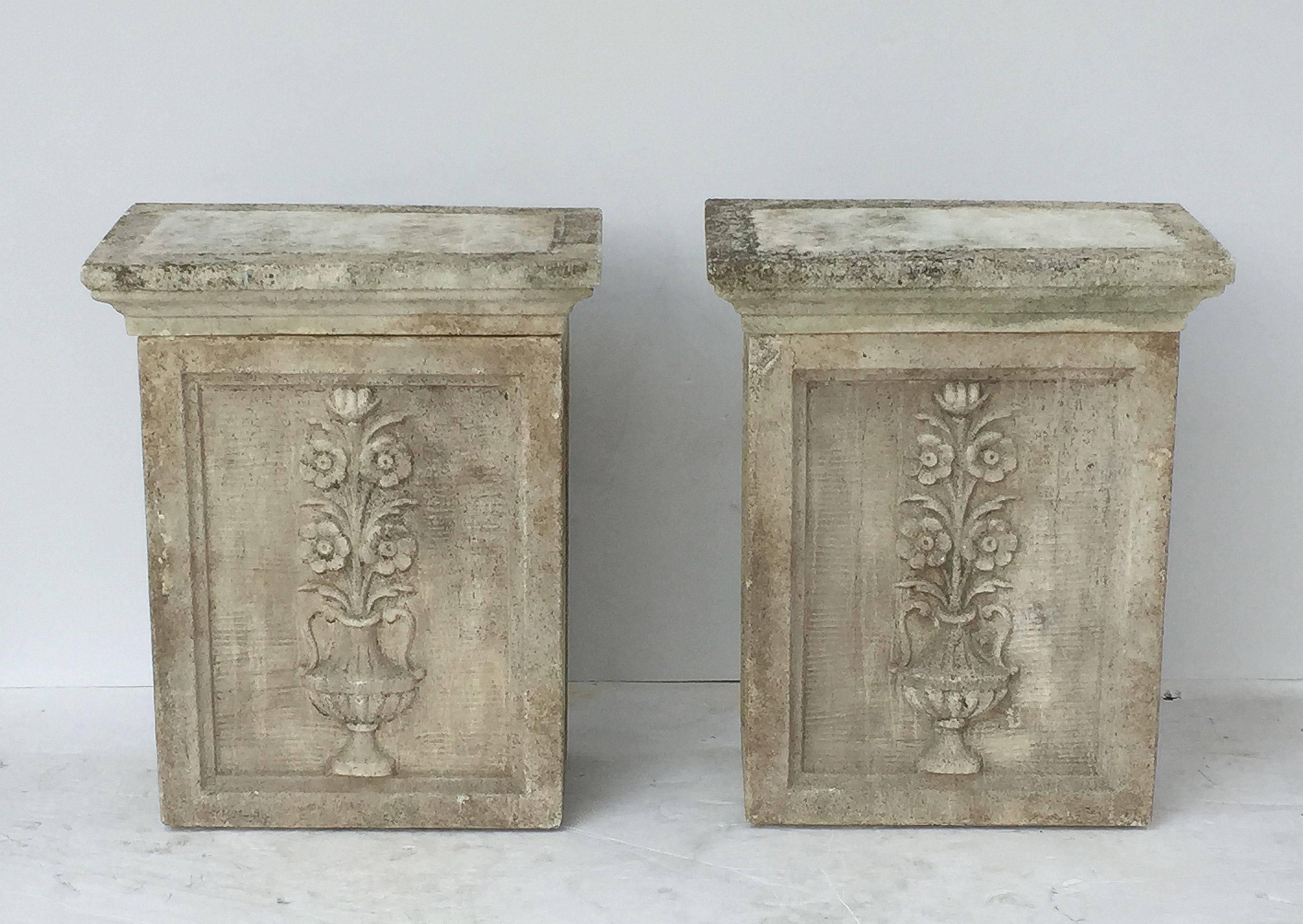 A fine pair of tall English rectangular garden pedestals or planter plinths of composition stone, each featuring a removable fitted plinth top set upon a pedestal base, with a relief of a Classical urn with flowers on opposing sides. 

Note: Each