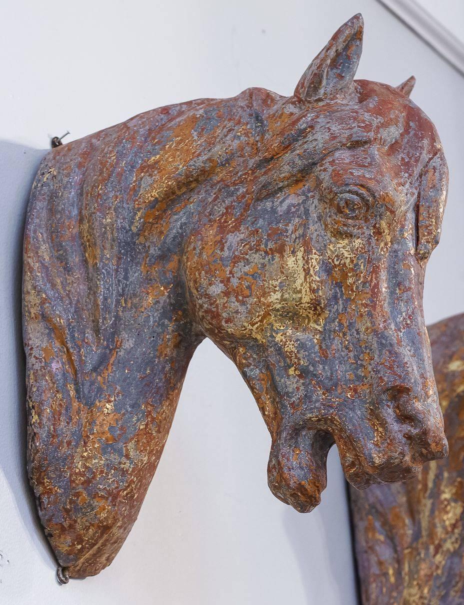 A decorative French hanging bust of a horse's head, fashioned of moulded zinc and featuring a handsome aged patina with traces of the original gilt finish.

With two hanging hooks attached. As it is hollow, it is not heavy for hanging.

Perfect