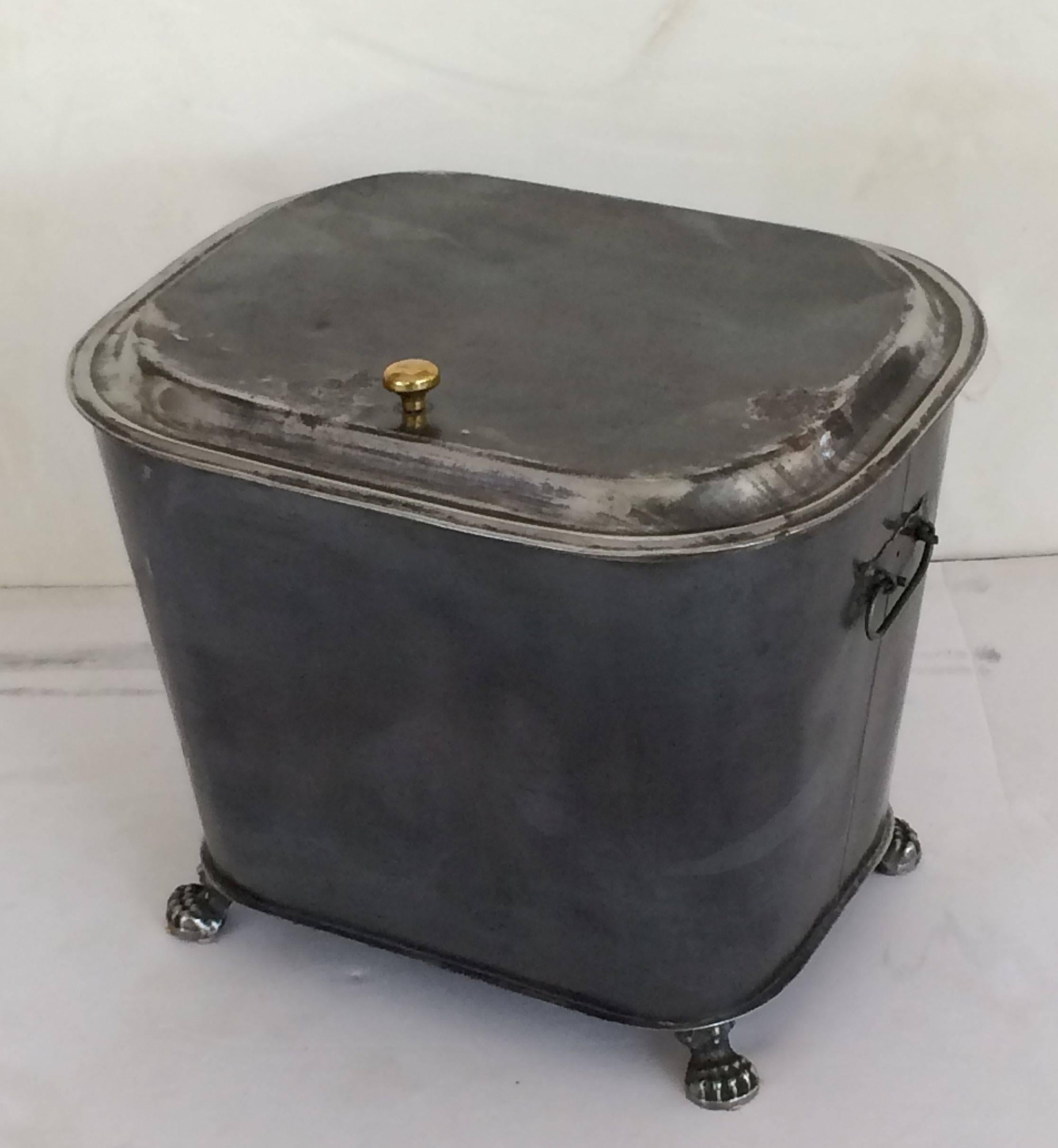 A fine English burnished steel bin with moulded hinged lid and brass pull, opposing handles, and resting on claw feet.

Its large size is great for a variety of storage.