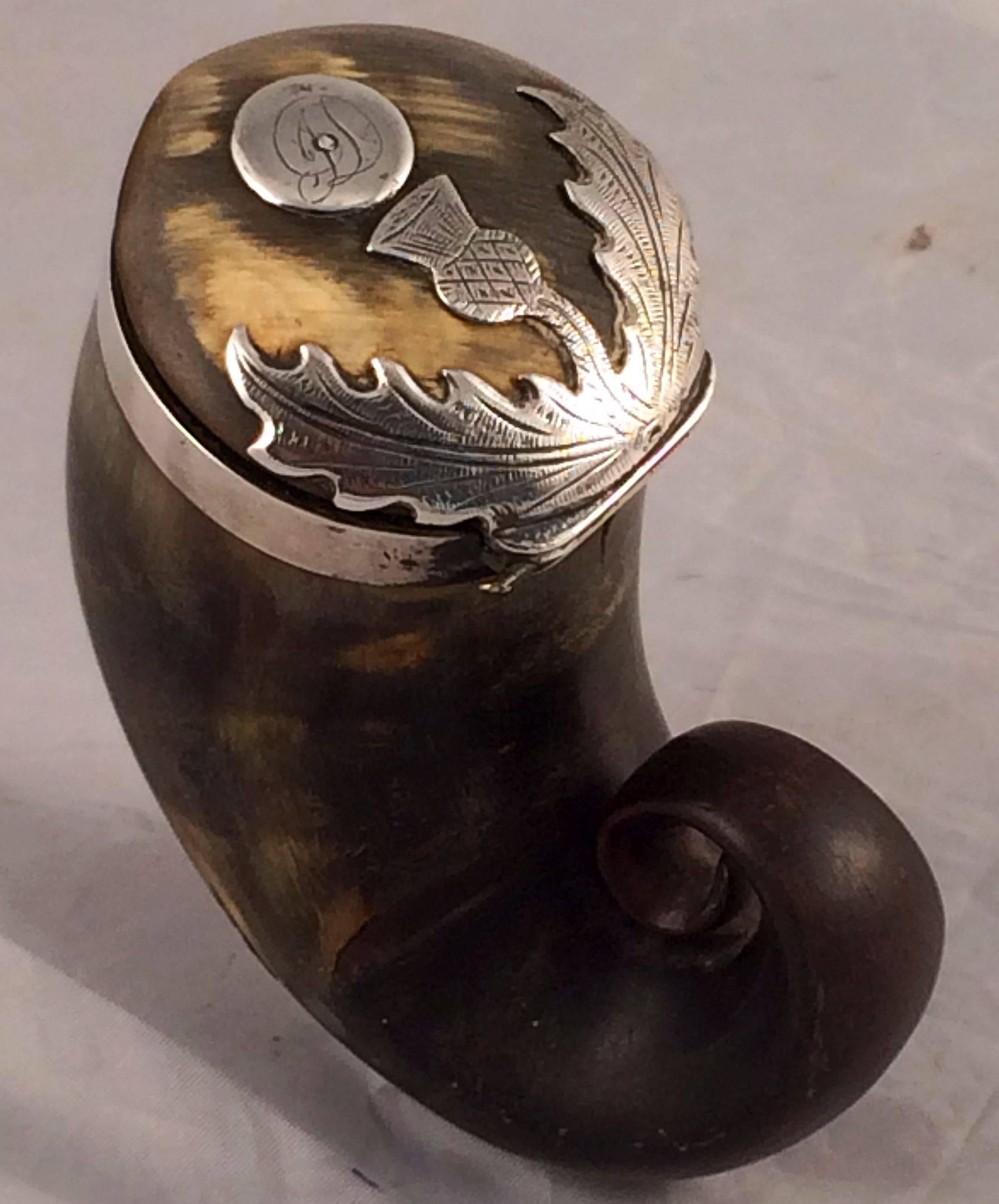 A handsome Scottish silver-mounted horn mull for snuff tobacco from the Georgian era, circa 1800, featuring an etched silver thistle (a symbol for Scotland) decorating the hinged lid.

Measuring: 3 1/4