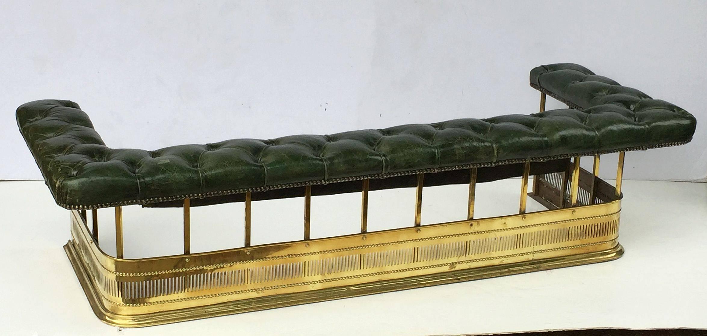 A fine English fireplace club fender or fireplace surround from the Edwardian era, featuring a tufted leather upholstered cushion seat with brass nail-head beading, mounted to a pierced rolled brass base.