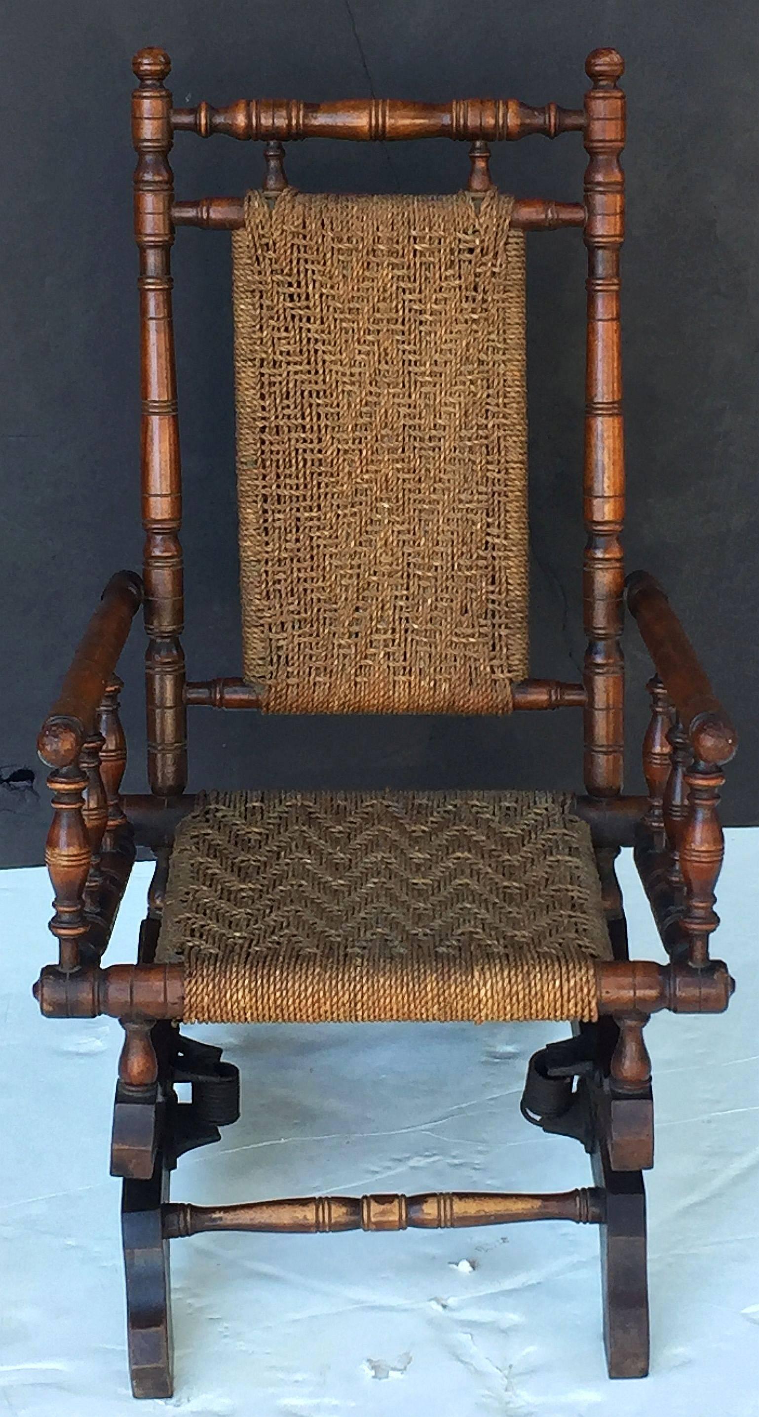 A fine English child's rocking chair in the American style, featuring the working design of an adult-sized chair but at a smaller scale.

Handsomely turned spindle frame with woven string or rope back and seat, mounted to a serpentine support with