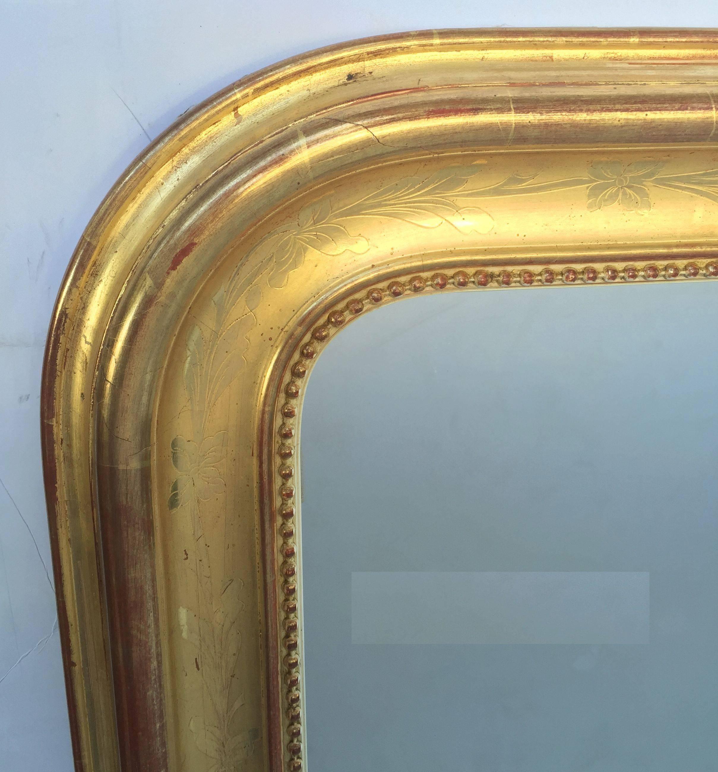 A handsome large Louis Philippe gilt wall mirror featuring a lovely moulded surround and an etched foliate design showing through gold-leaf.

Dimensions: H 51 3/4