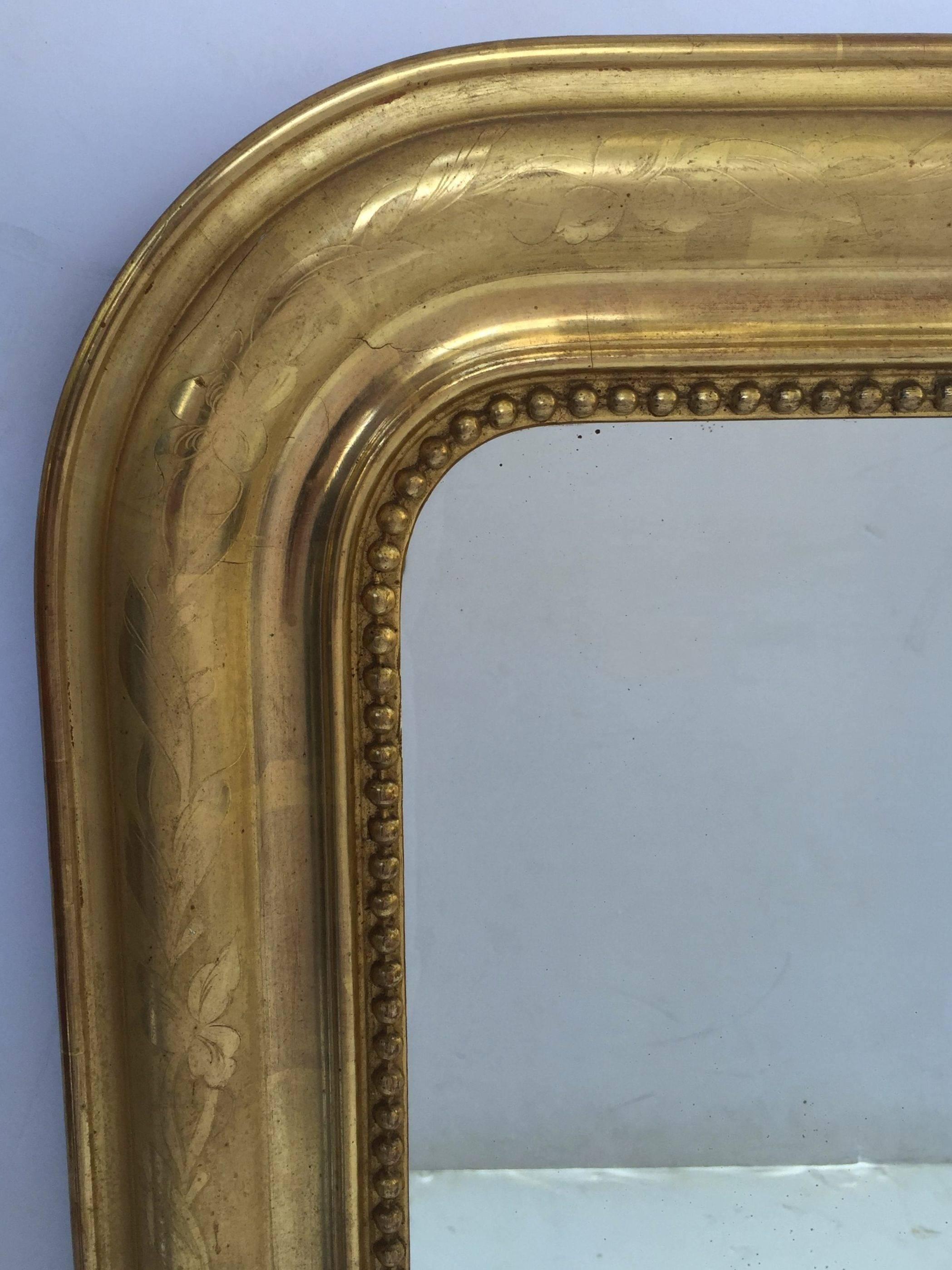 A handsome large Louis Philippe gilt wall mirror featuring a lovely moulded surround and an etched foliate design showing through gold-leaf.

Dimensions: H 35 1/2