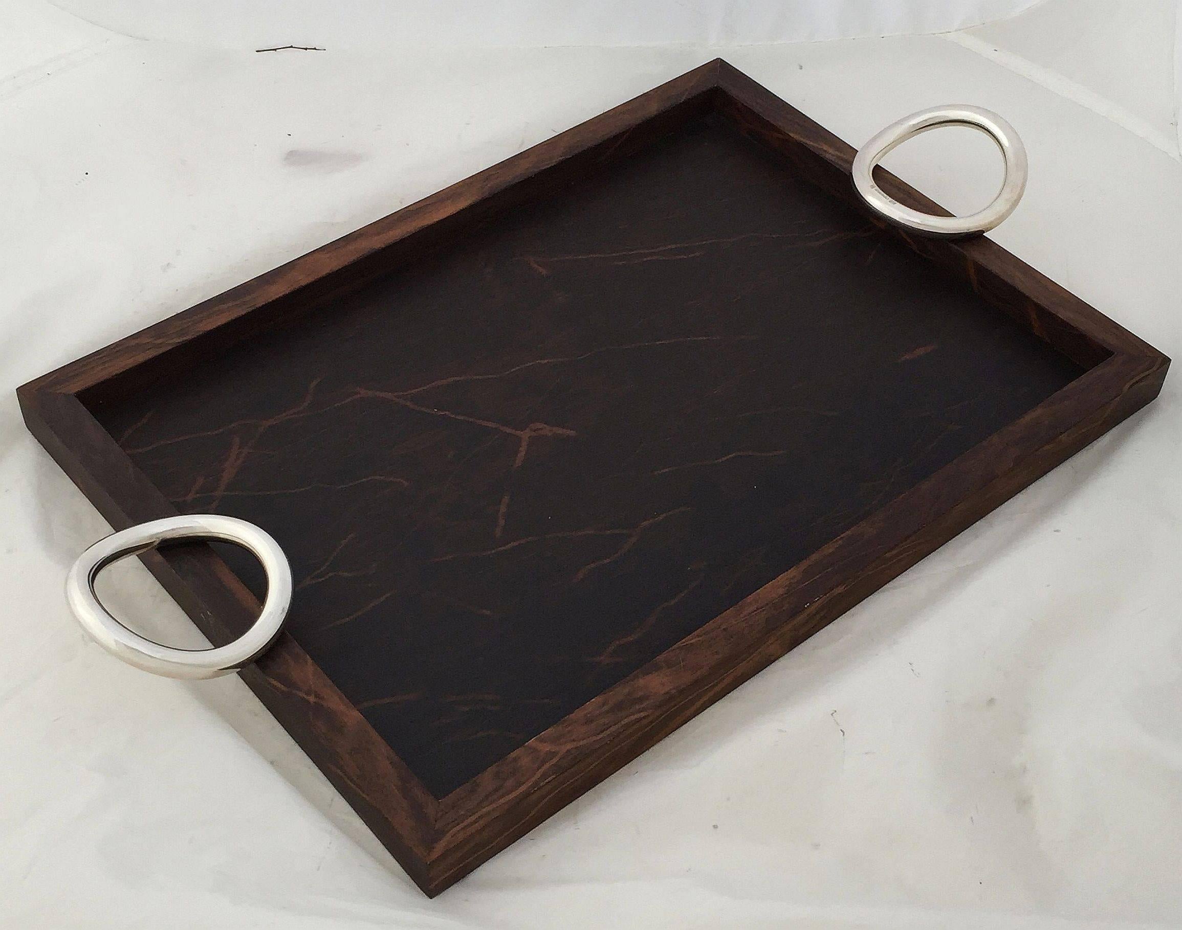 A handsome rectangular serving tray by the celebrated French design company, Christofle, featuring a design of wood with silver ring handles by Andrée Putnam.

Andrée Putman (23 December 1925 – 19 January 2013) was an important French interior