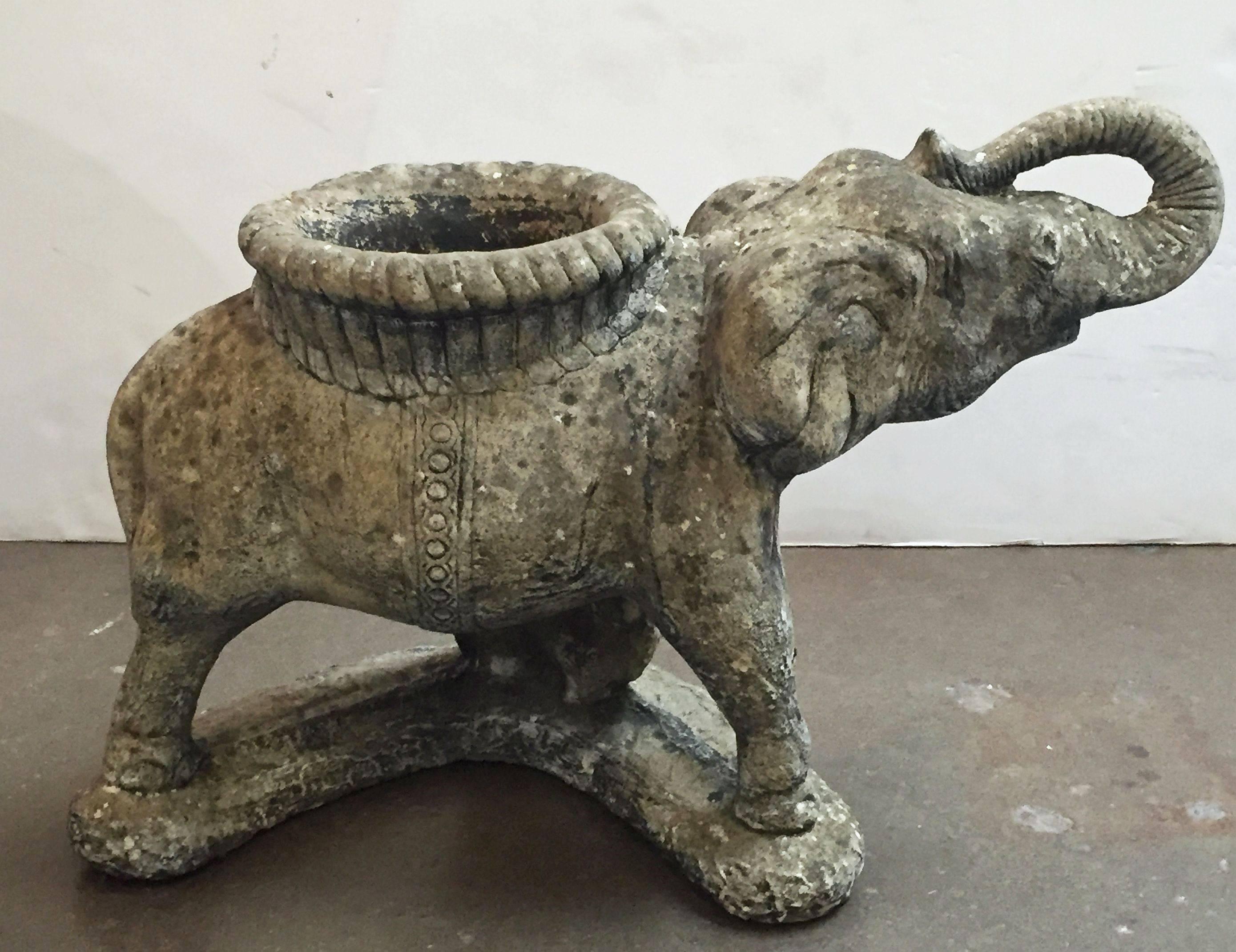 A large English garden planter, of composition stone, in the form of an elephant with raised trunk and howdah (seat) serving as planter.