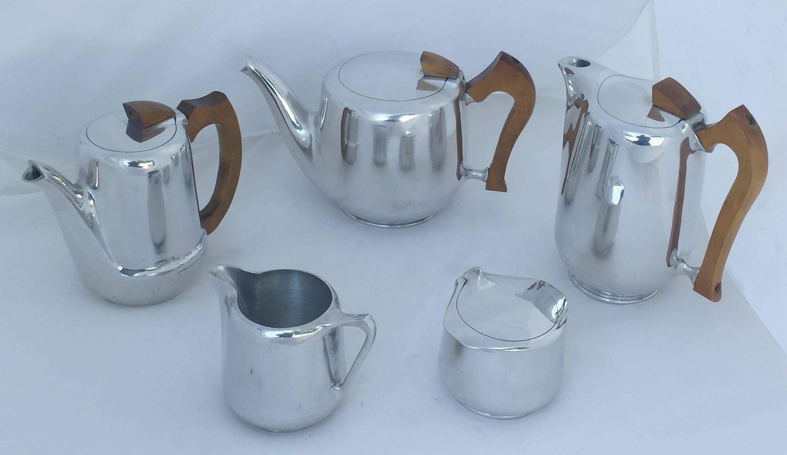 A handsome five-piece English tea and coffee set by Picquot, includes a lidded tea pot with handle, a lidded coffee pot with handle, a lidded hot water carafe with handle, and lidded sugar and creamer, all featuring the stylish mid-century design