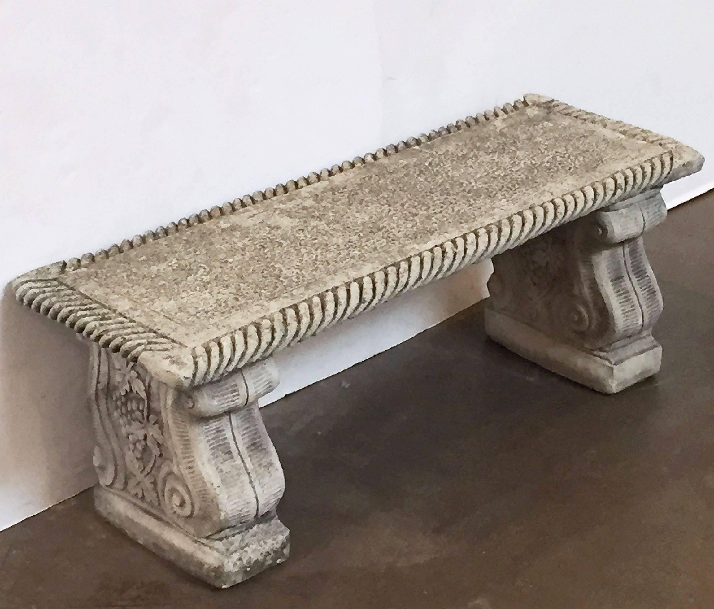 A handsome English garden long bench or seat of composition stone, featuring a gadroon-edge rectangular top set upon two scroll supports with a relief design of grapes and grape leaves.

Dimensions: H 16