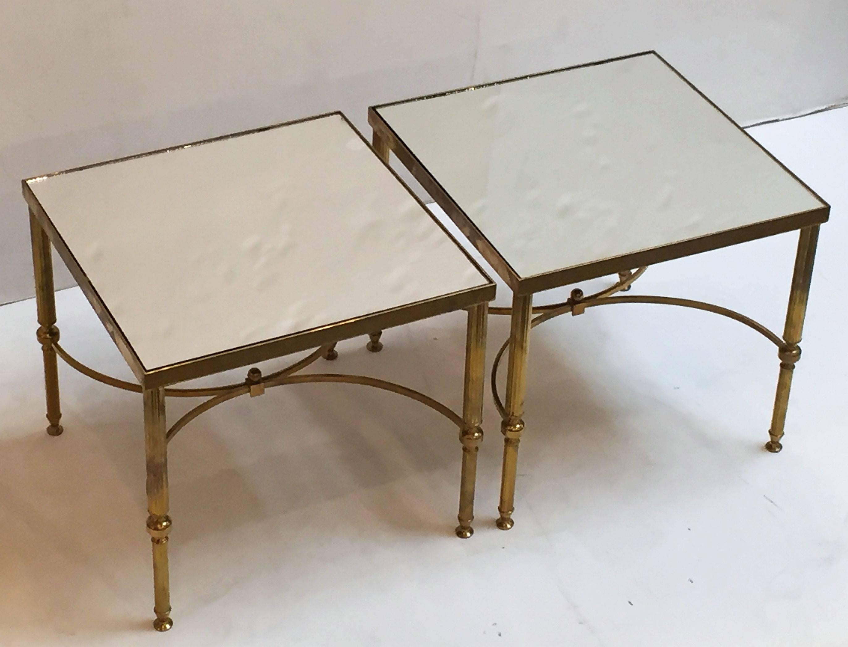 A fine pair of square French low side or end tables of brass with mirrored glass tops, opposing demilune stretchers and reeded, tapering legs.

Individually priced - $1595 each table.