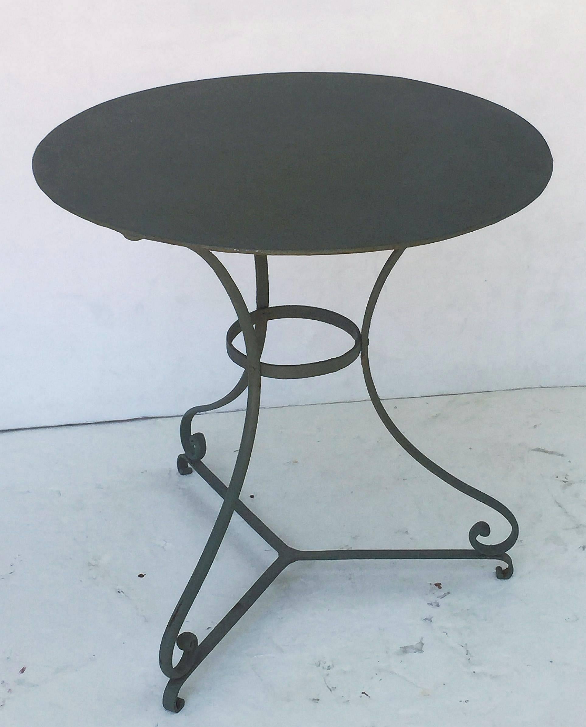 A fine French green-painted café or bistro pub table featuring a round or circular metal top, attached to a tripod base with serpentine legs and tripod stretcher.

Great for an indoor or outdoor garden, garden room, or patio

Measures: Height 28