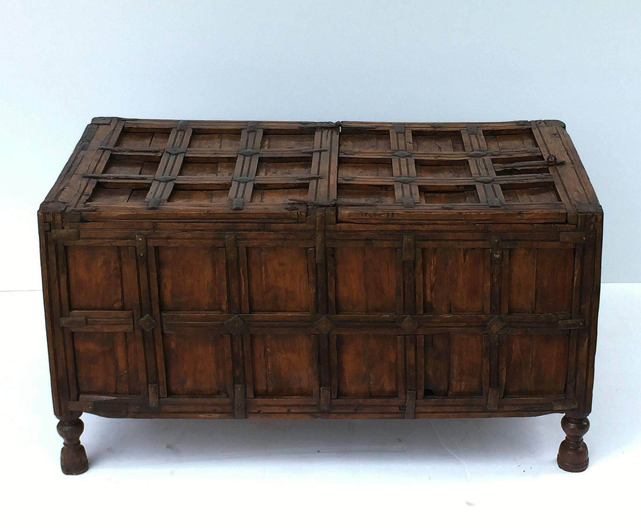 A handsome 19th century iron-bound wooden stick box or coffer from British Colonial India featuring a hinged top hatch with storage inside. 
The paneled trunk with original ribbed iron fittings and standing on turned feet.

Traditionally used for