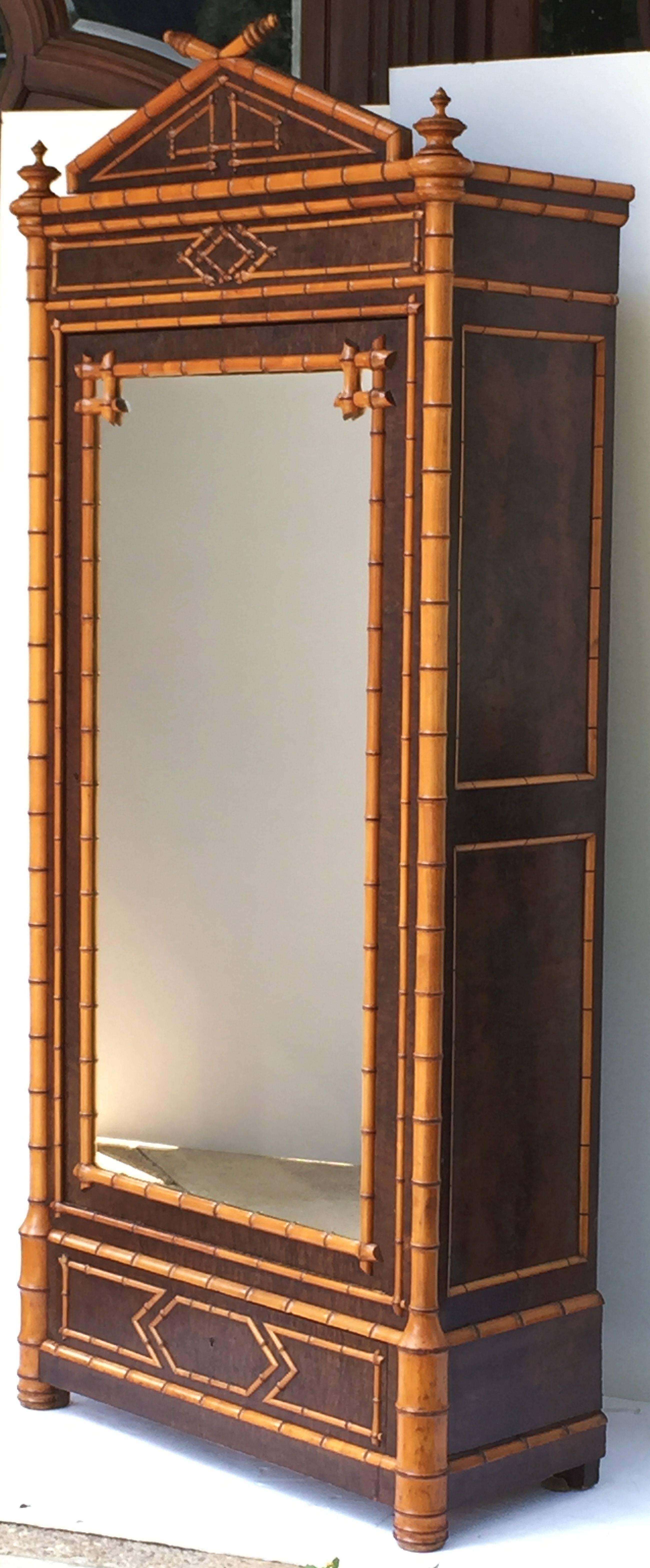 A fine French faux bamboo armoire (or bookcase and display cabinet) of two-toned birds-eye or curly maple featuring a canopy top with decorative finials, over a glass or glazed door enclosing a cupboard space with adjustable shelves, each with faux