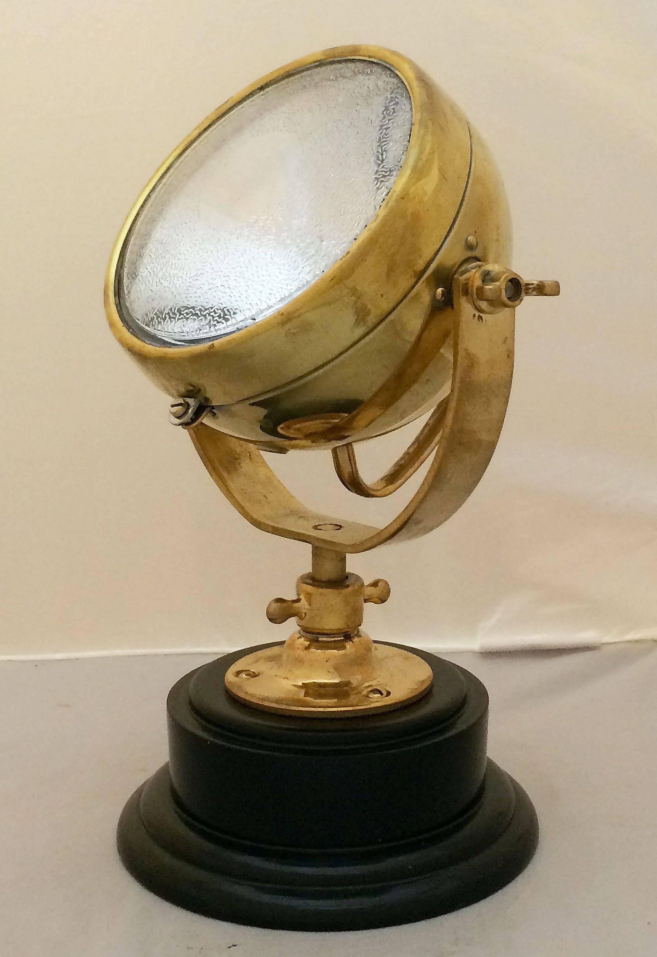 A vintage English adjustable fire truck or marine search light (lamp or lantern) of brass, mounted to a round ebonized wooden stand by Raydyot, circa 1940.

With brass stamp: Made in England, Raydyot.