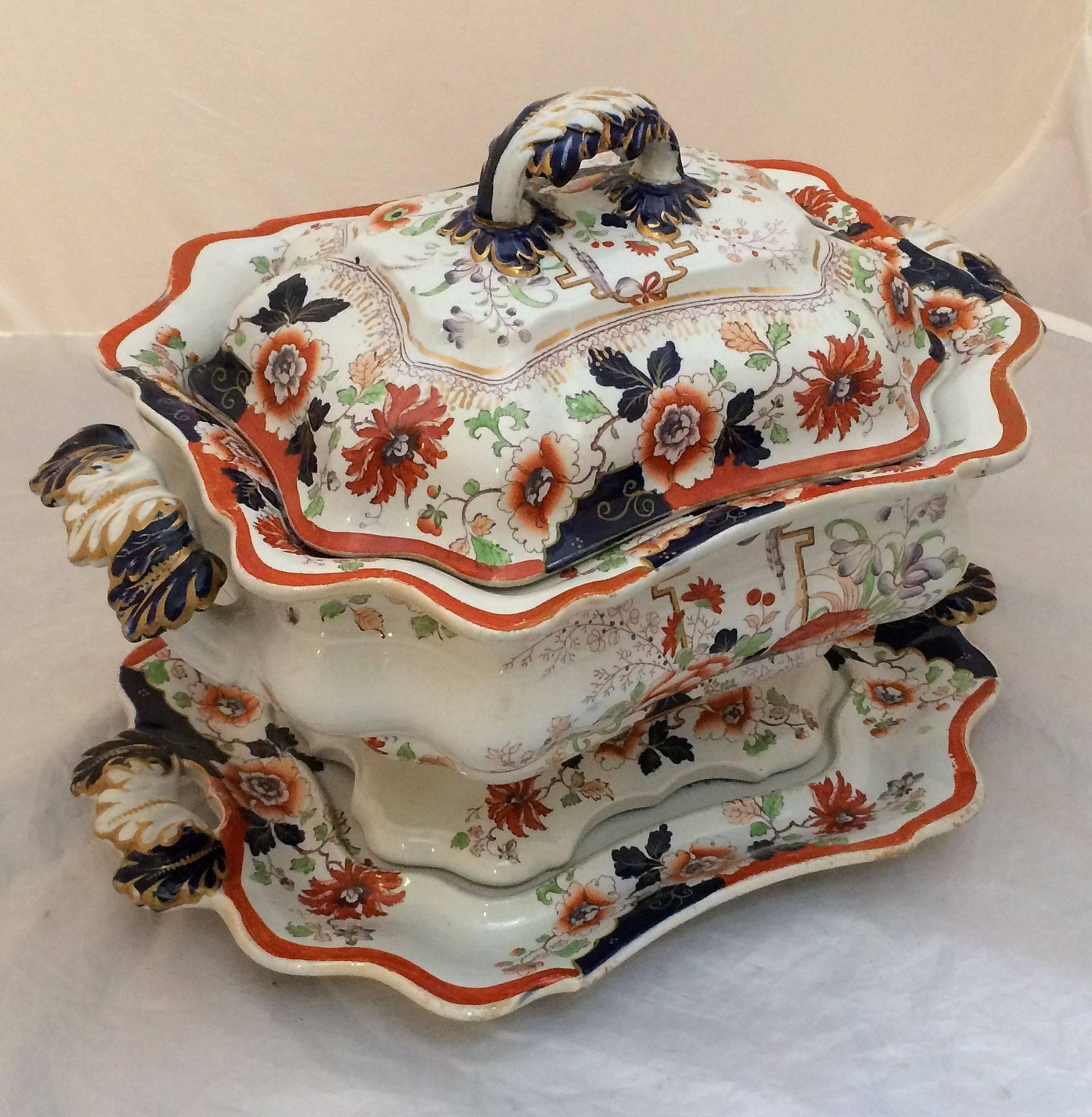 A fine English ironstone covered tureen with removable lid and under-tray from the early 19th century, featuring a lovely poly-chrome pattern and gilt and cobalt blue accents on the body and handles.

With mark: Real Iron-Stone China (and British