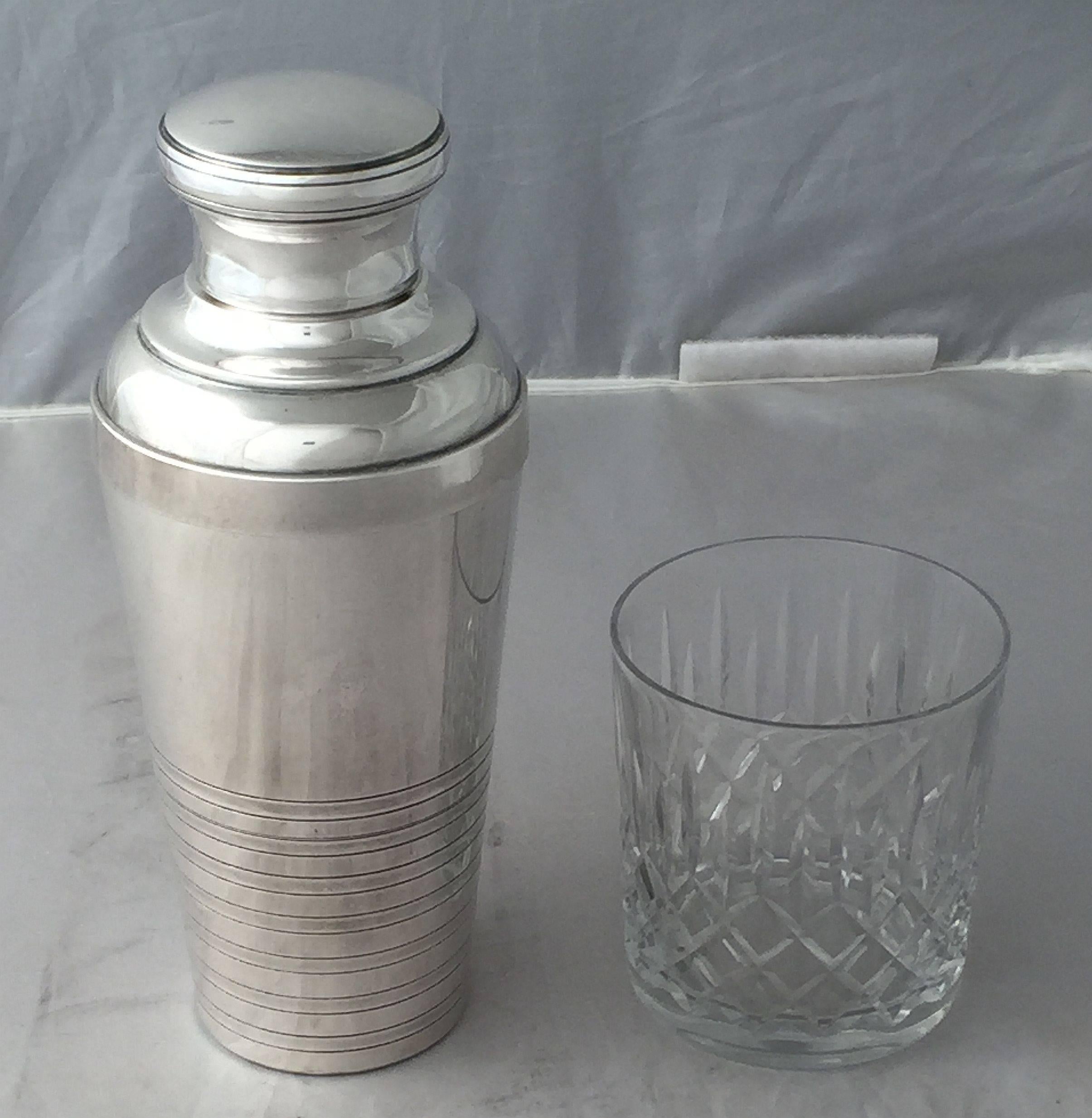 An authentic French cylindrical martini or cocktail shaker of fine plate silver featuring stylish Art Deco design, with removable cap and strainer.

