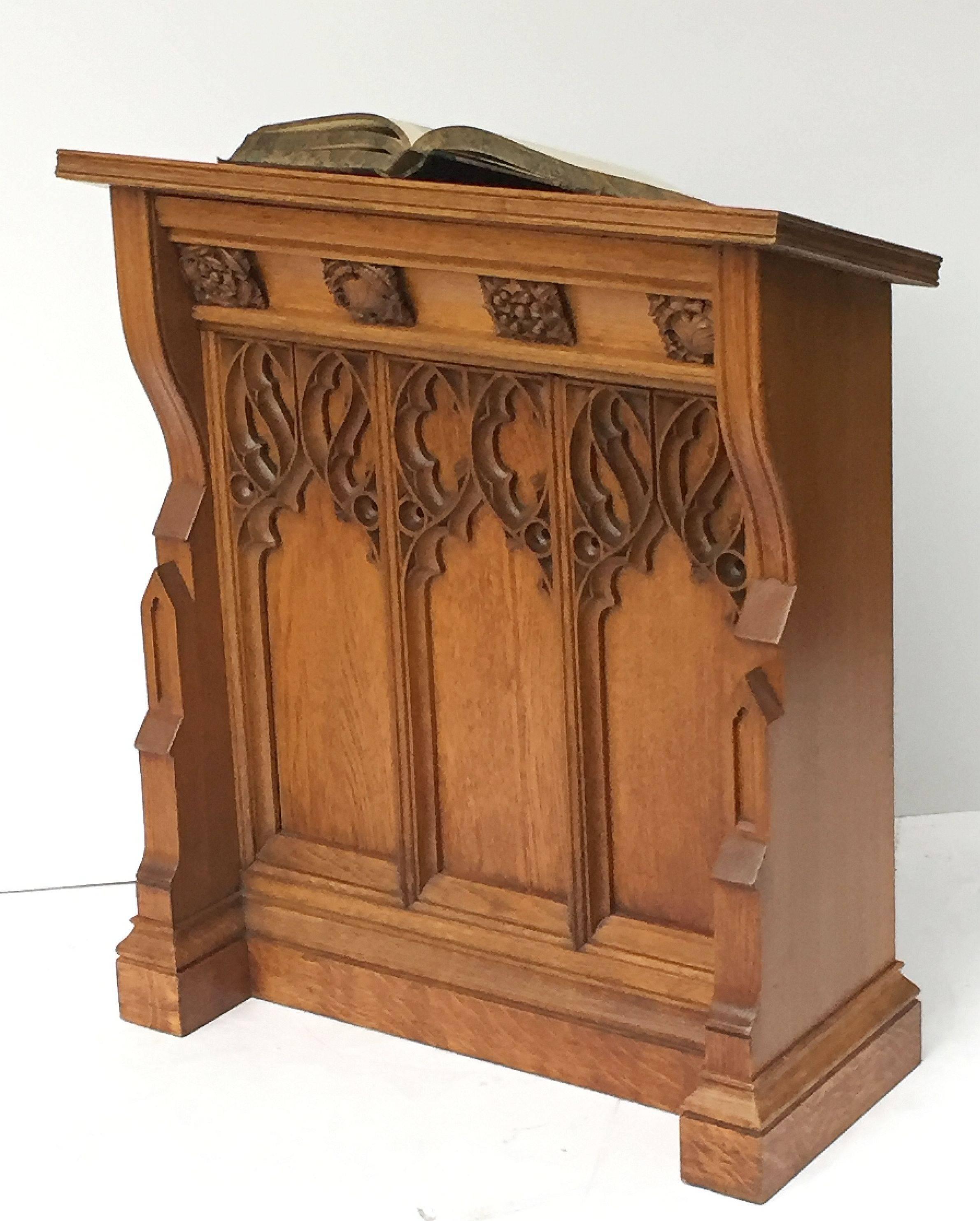 A handsome large English ecclesiastical standing lectern of oak in the Gothic style, featuring one side with slanted stand with support rest for a book, the other side paneled with carved Gothic designs, on a moulded plinth base.

Perfect for a