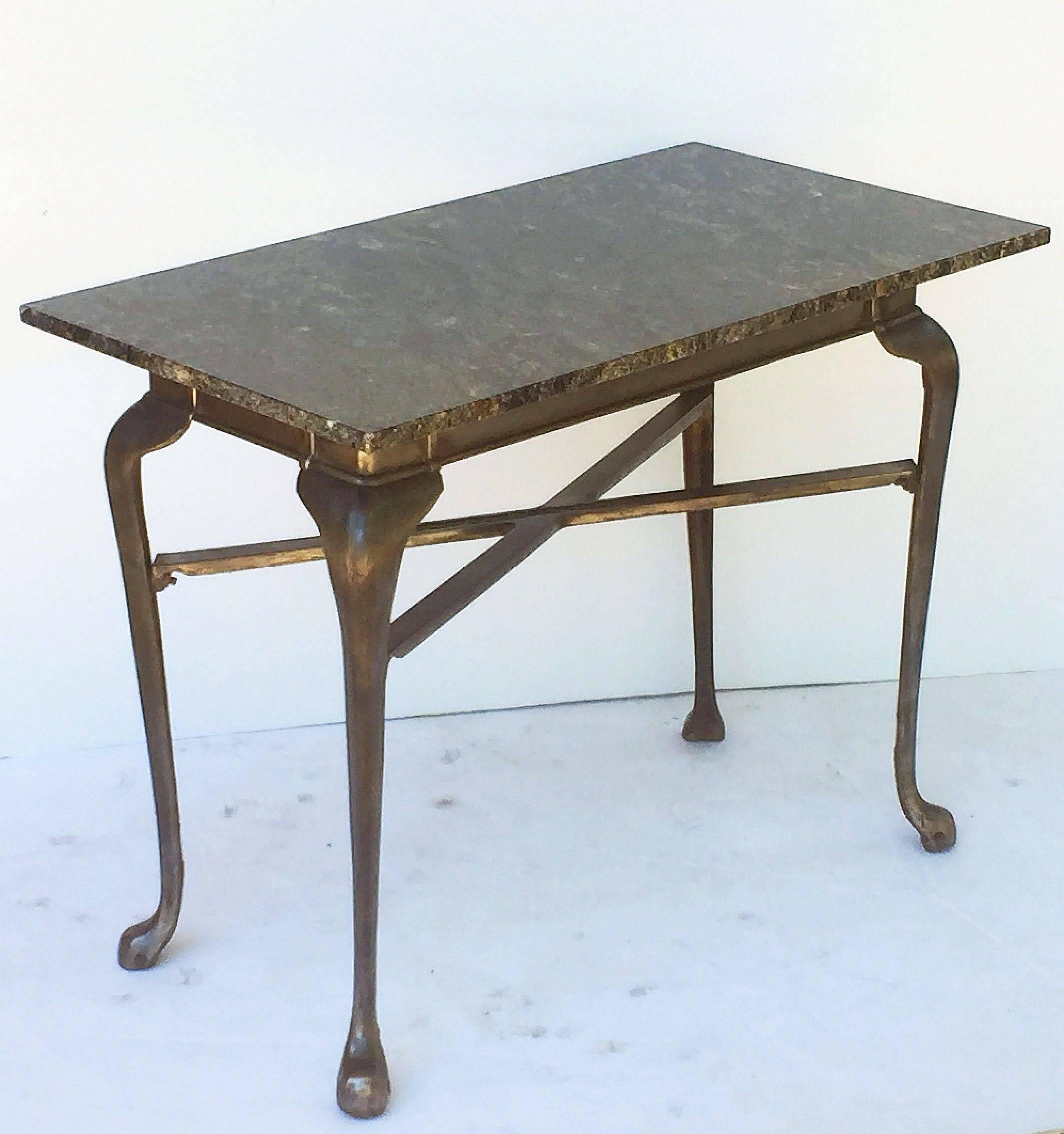 A fine English pub or bistro table of cast iron, made by Lawn and Howarth, Manchester, with a removable rectangular top of figured granite, set upon the iron base featuring a frieze with four cabriole legs and crossbar stretcher.

The stretcher
