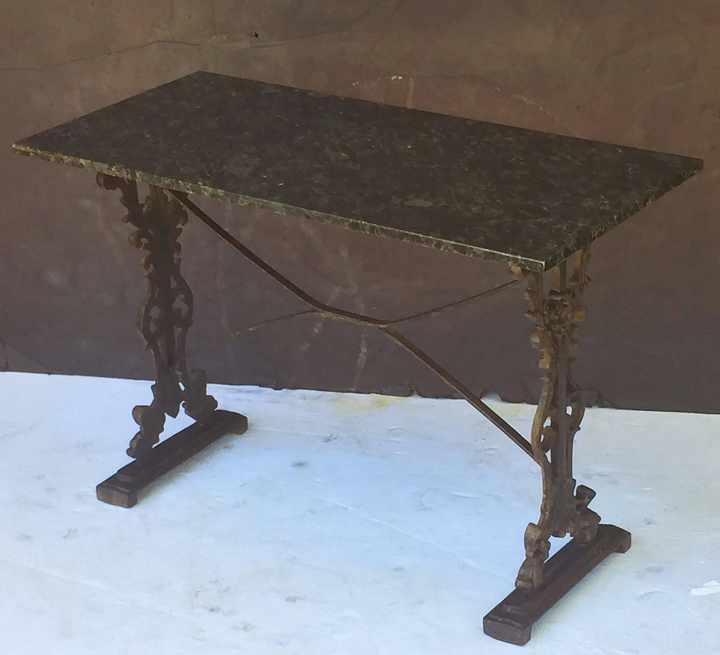 A pair of handsome English pub or bistro tables - each with a figured, rectangular granite top with a wood mount below, set upon a cast iron base with fine scroll work and sturdy bracket feet.

There are two available for sale.
Individually priced -