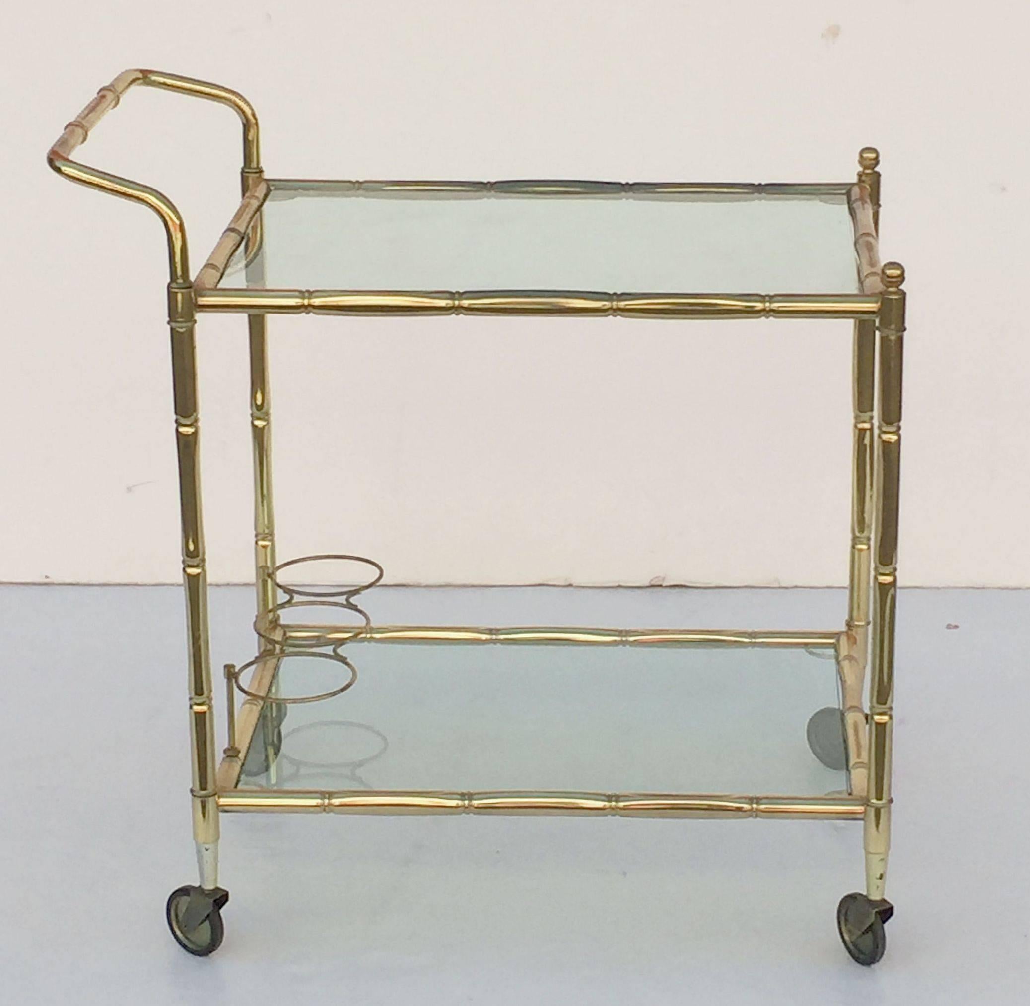 A handsome vintage French rectangular bar cart table or serving trolley in brass with a bamboo design, and featuring two tinted glass tiers, with bottle rack on second tier, on rolling caster wheels. 

Perfect for use as a side or end table.
