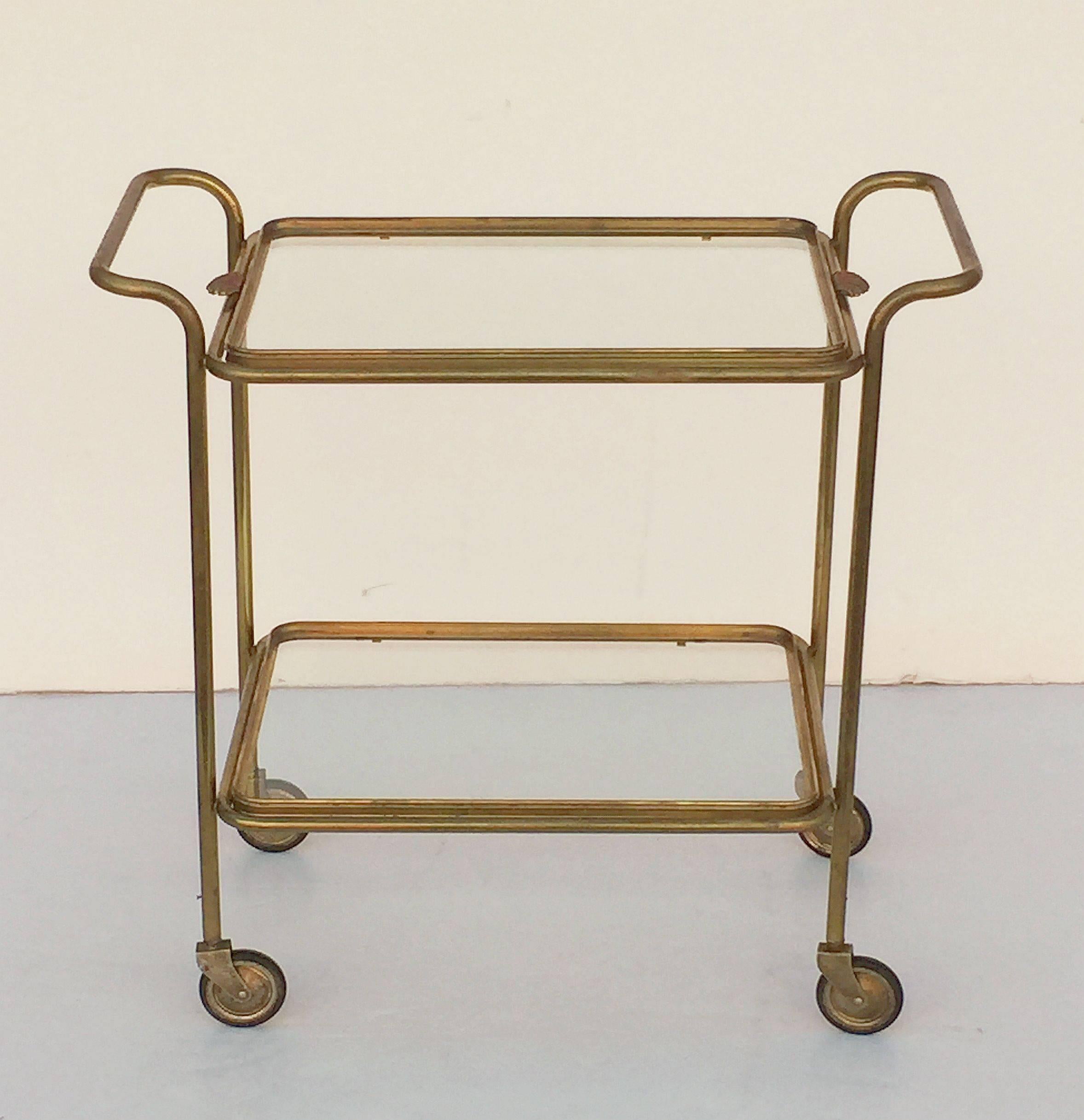 A handsome vintage French rectangular bar cart (drinks table) or serving trolley in brass, with two glass selves, on rolling caster wheels. 

The top tier is removable for use as a serving tray and features a shell design for the handles at each