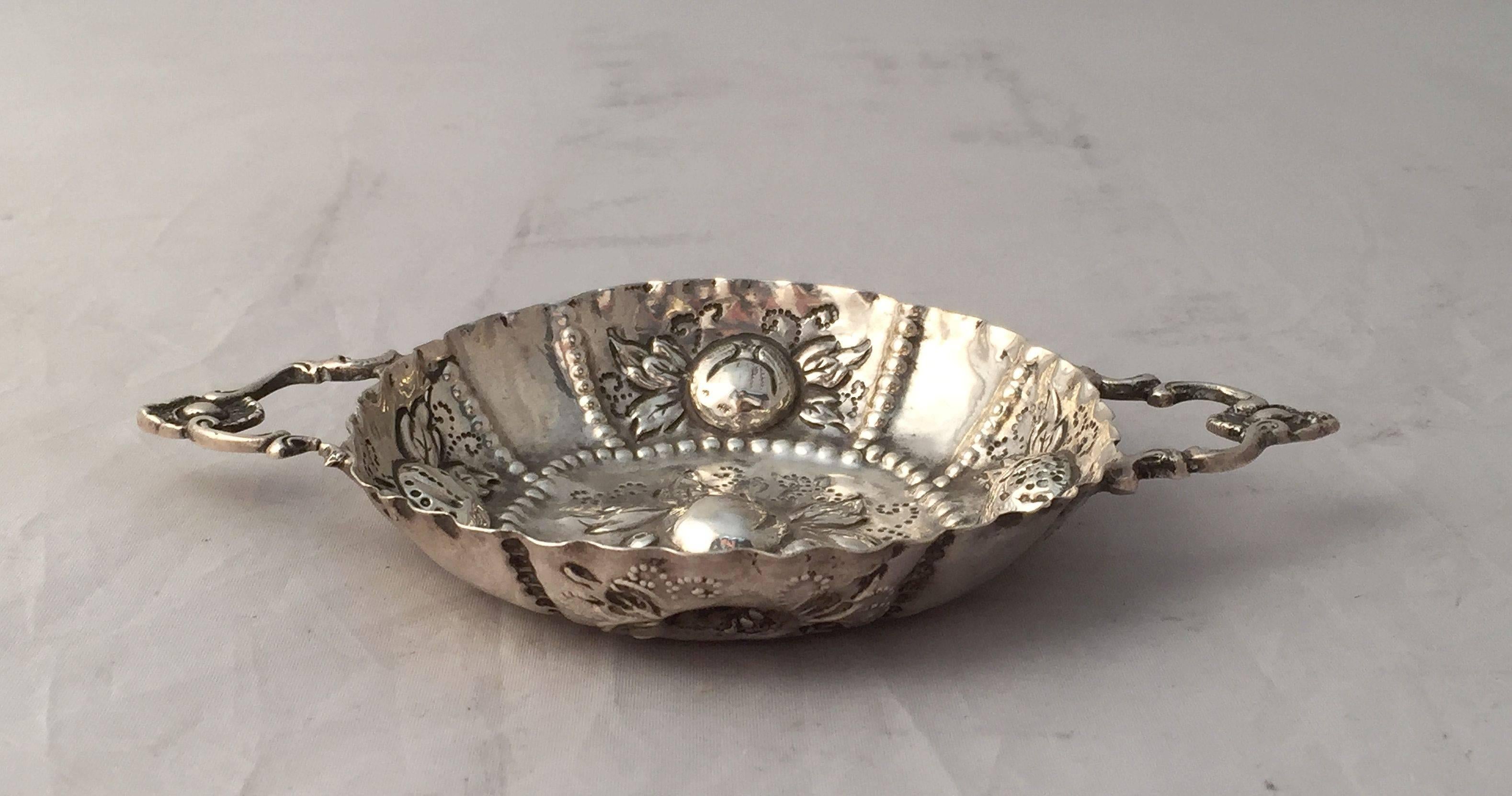 A fine wine taster or tasting dish from Germany, circa 1890, featuring an embossed design of fruit, serpentine edge, and two handles

Impressed mark: 800 silver.

Originally created by wine makers in order to assess the clarity and color of wine