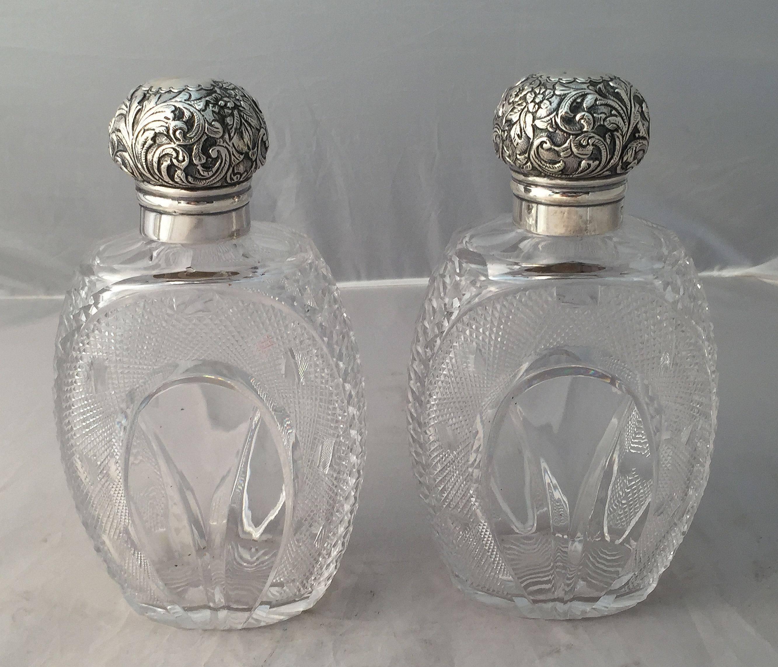 A fine pair of large English cut crystal bottles or decanters with sterling silver tops, each bottle featuring a chased foliate cap with hallmarks for London, circa 1889, over a finely cut crystal ovoid body.

Two available, priced individually,
