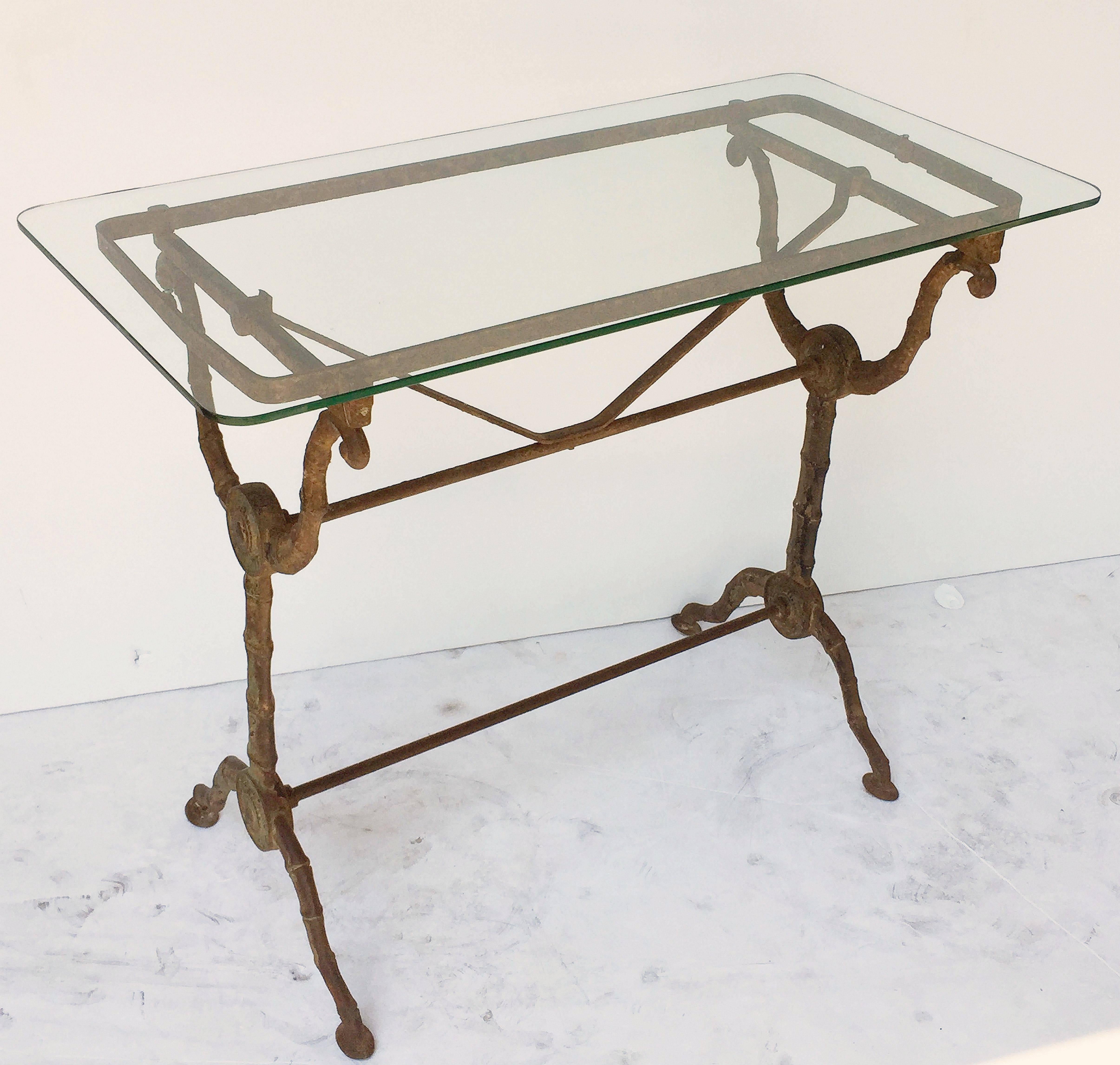 A pair of handsome English pub or bistro tables, each with a rectangular clear glass top, set upon a cast iron base with fine scroll work and sturdy segmented or faux bamboo supports.

There are two available for sale.
Individually priced - $2995