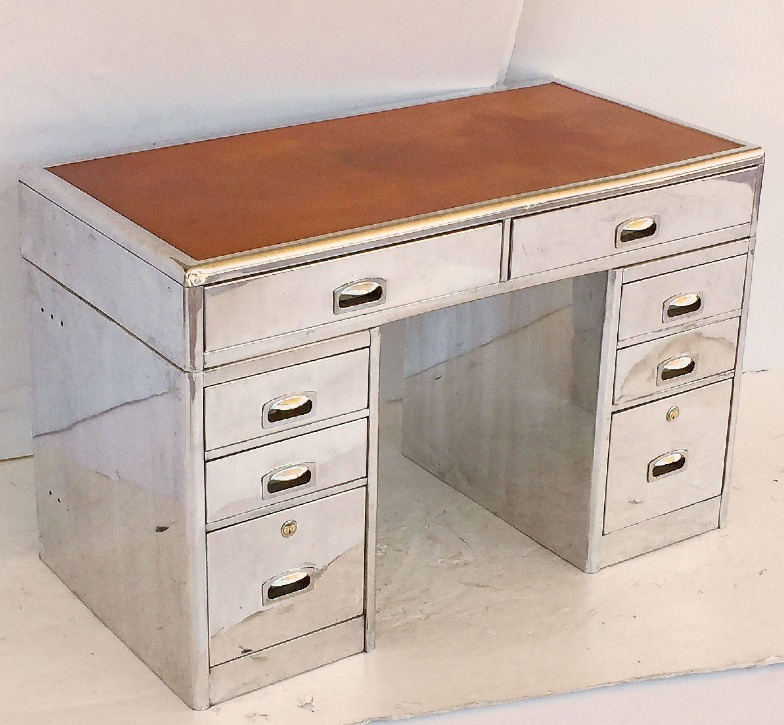 A handsome English mariner's or nautical yachtsman's pedestal desk of polished aluminium with leather top.
Featuring a rectangular top with embossed leather writing surface, rounded corners and top edge over a frieze of two metal drawers, each with