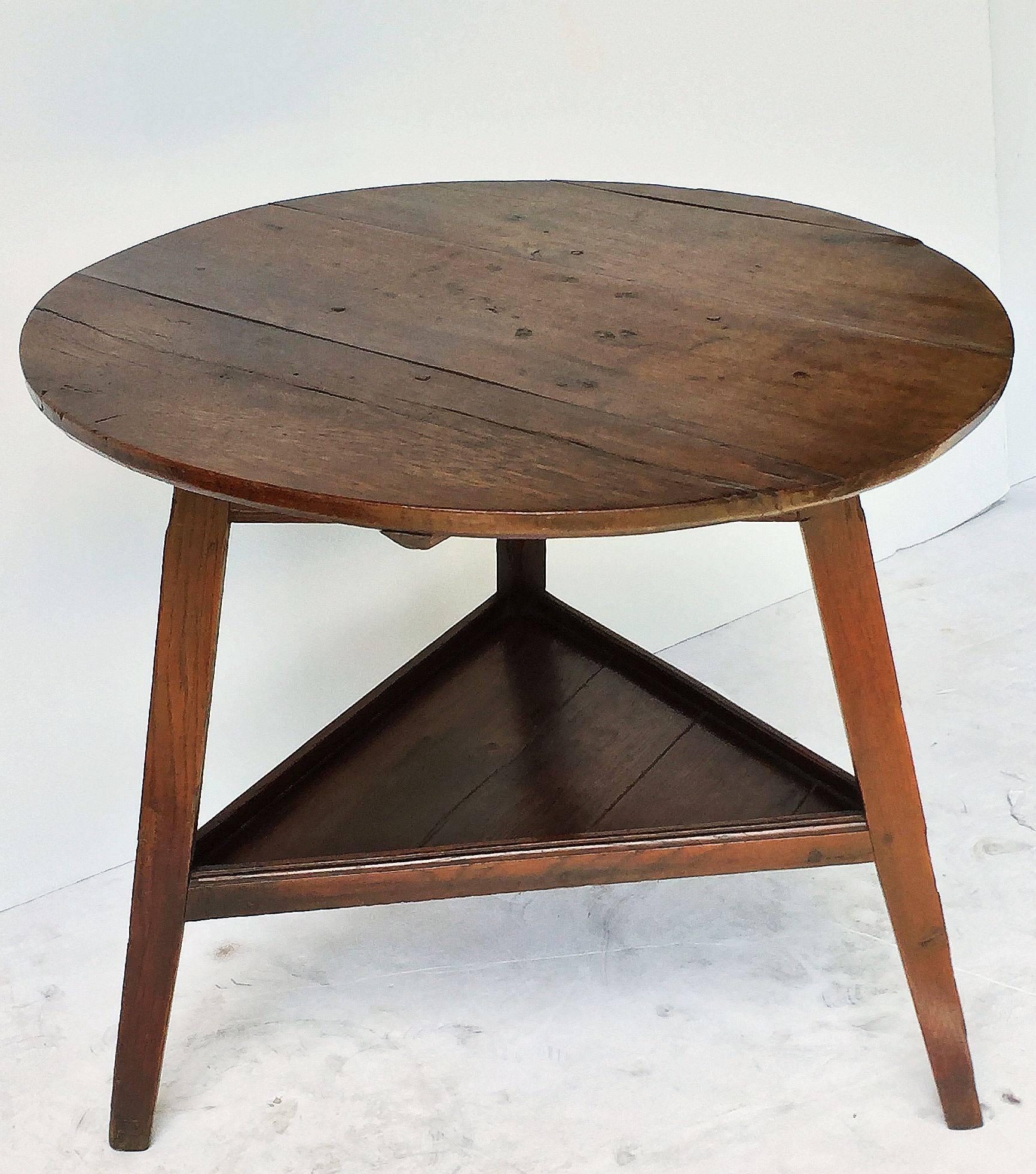 A fine English cricket table of oak featuring the traditional round or circular top over a tripod base triangular under-tier shelf.

Makes a nice occasional table or side table.