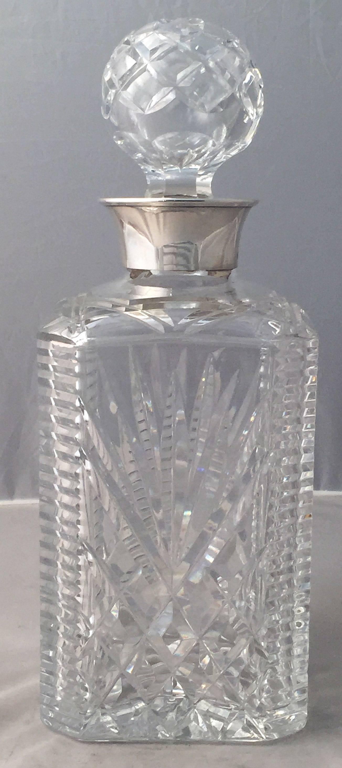 A handsome English four-sided spirits or whiskey decanter of faceted cut crystal with sterling silver collar and removable round stopper.

Hallmarks for Birmingham.