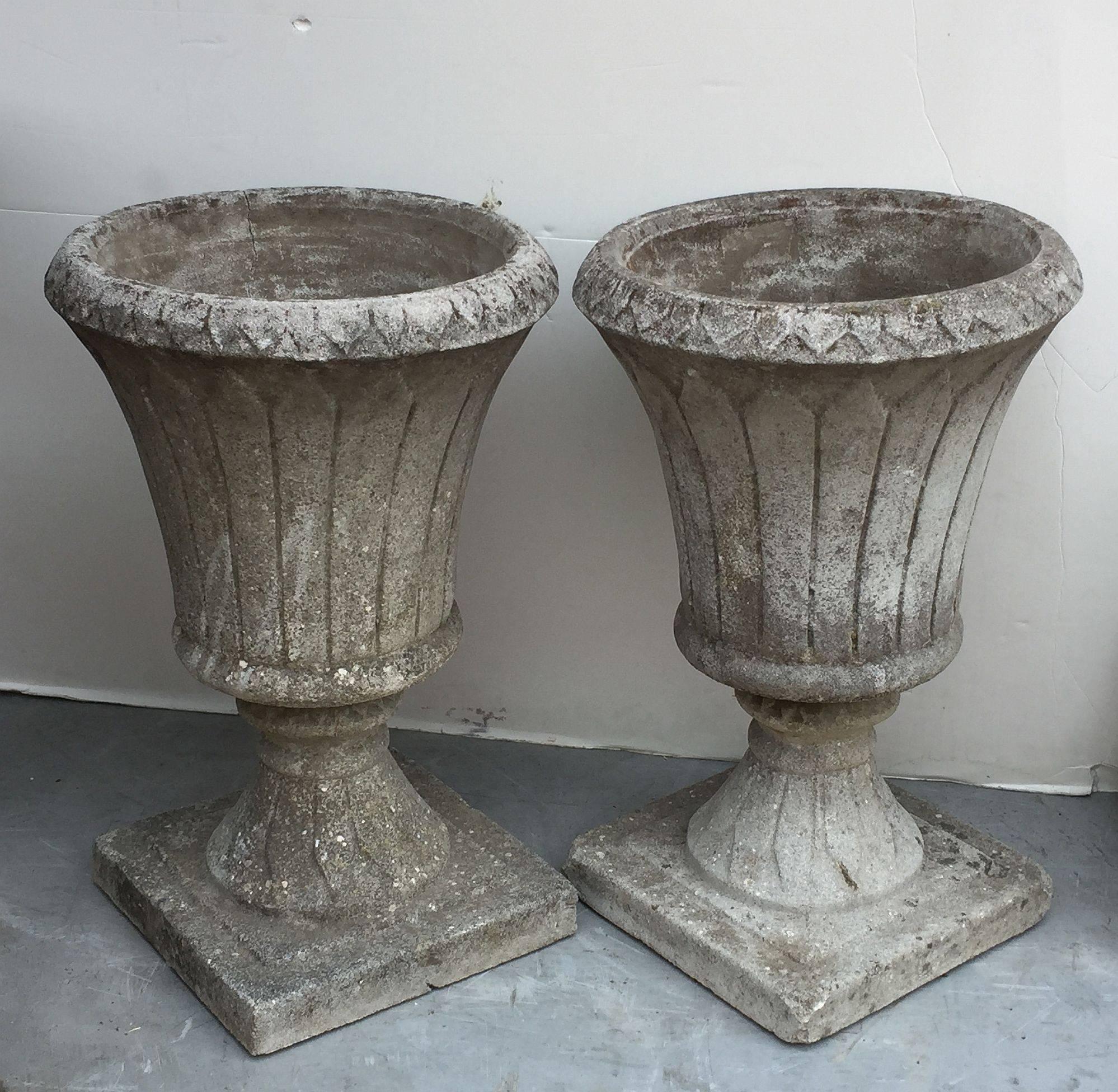 A fine pair of English garden urns or planters of composition stone in the classical style, each bowl featuring an stylized edge over a fluted column and raised square base.

Great for an indoor or outdoor garden room, garden, or