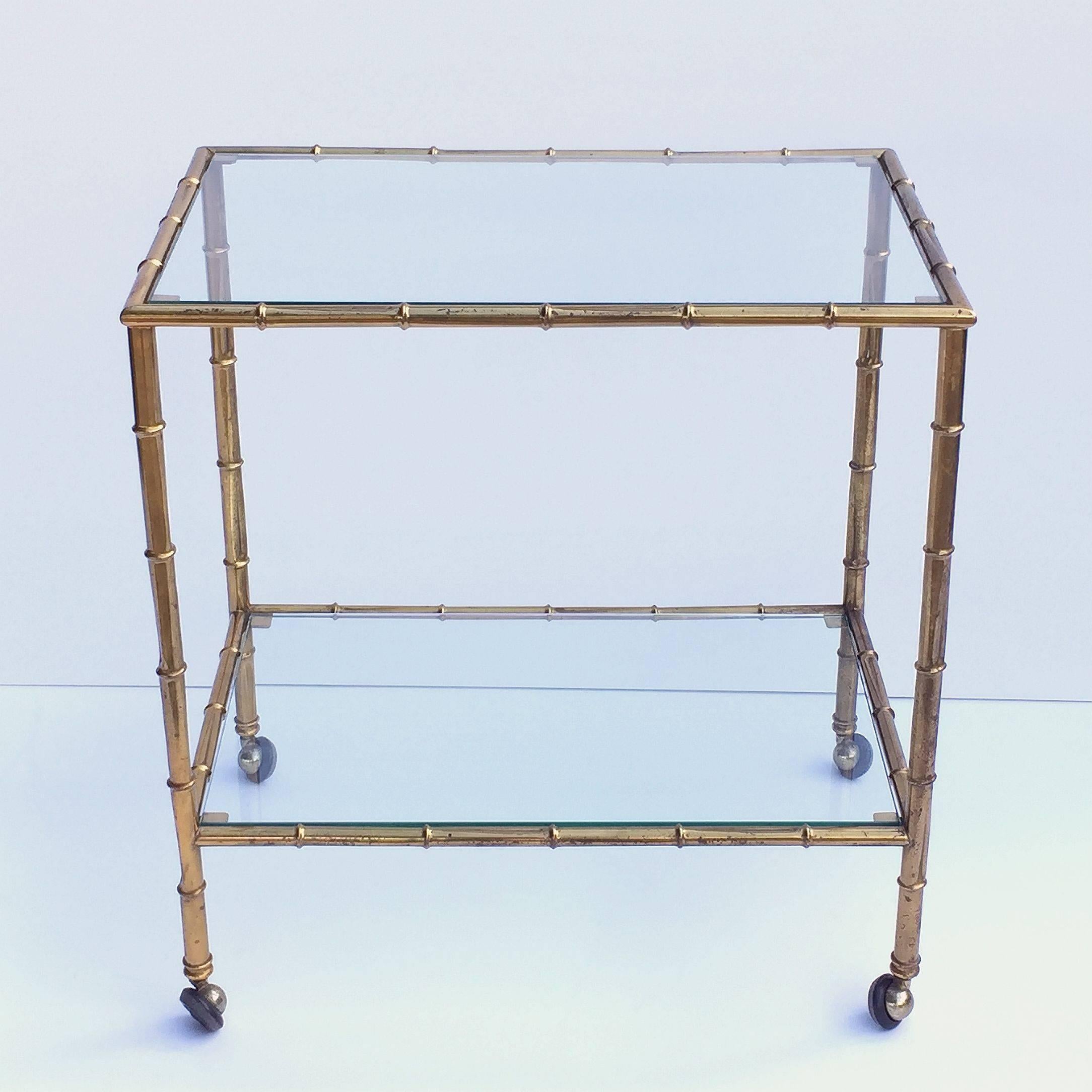 A handsome vintage French rectangular bar cart table or serving trolley in brass with a bamboo design, and featuring two glass tiers, on rolling caster wheels. 

Perfect for use as a side or end table.