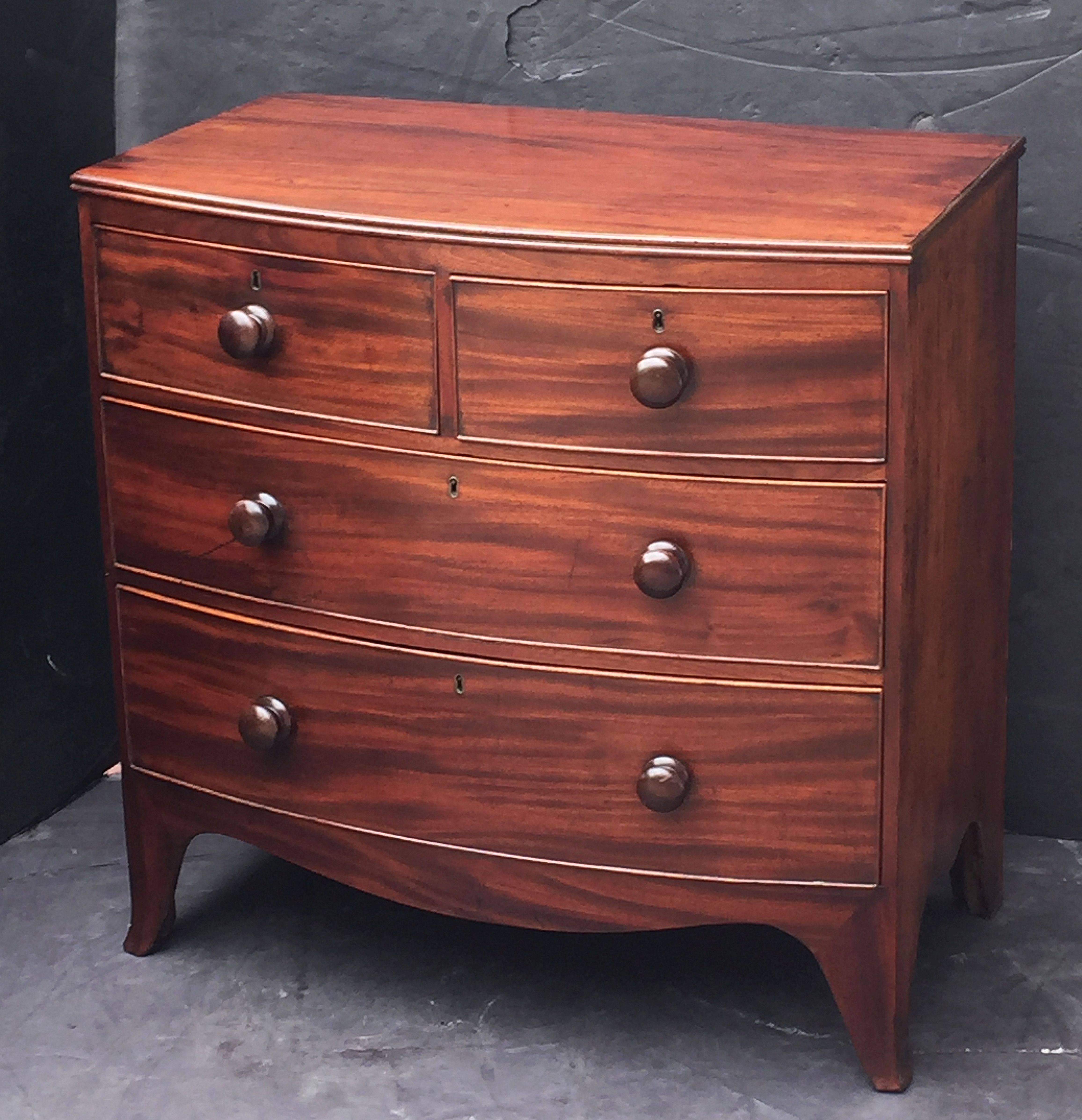 A handsome English bow-front chest of drawers of mahogany, featuring a bowed top over a frieze of two small beaded drawers and two beaded long drawers, with knob pulls, and set upon a serpentine splayed foot base.
The drawers showing mahogany