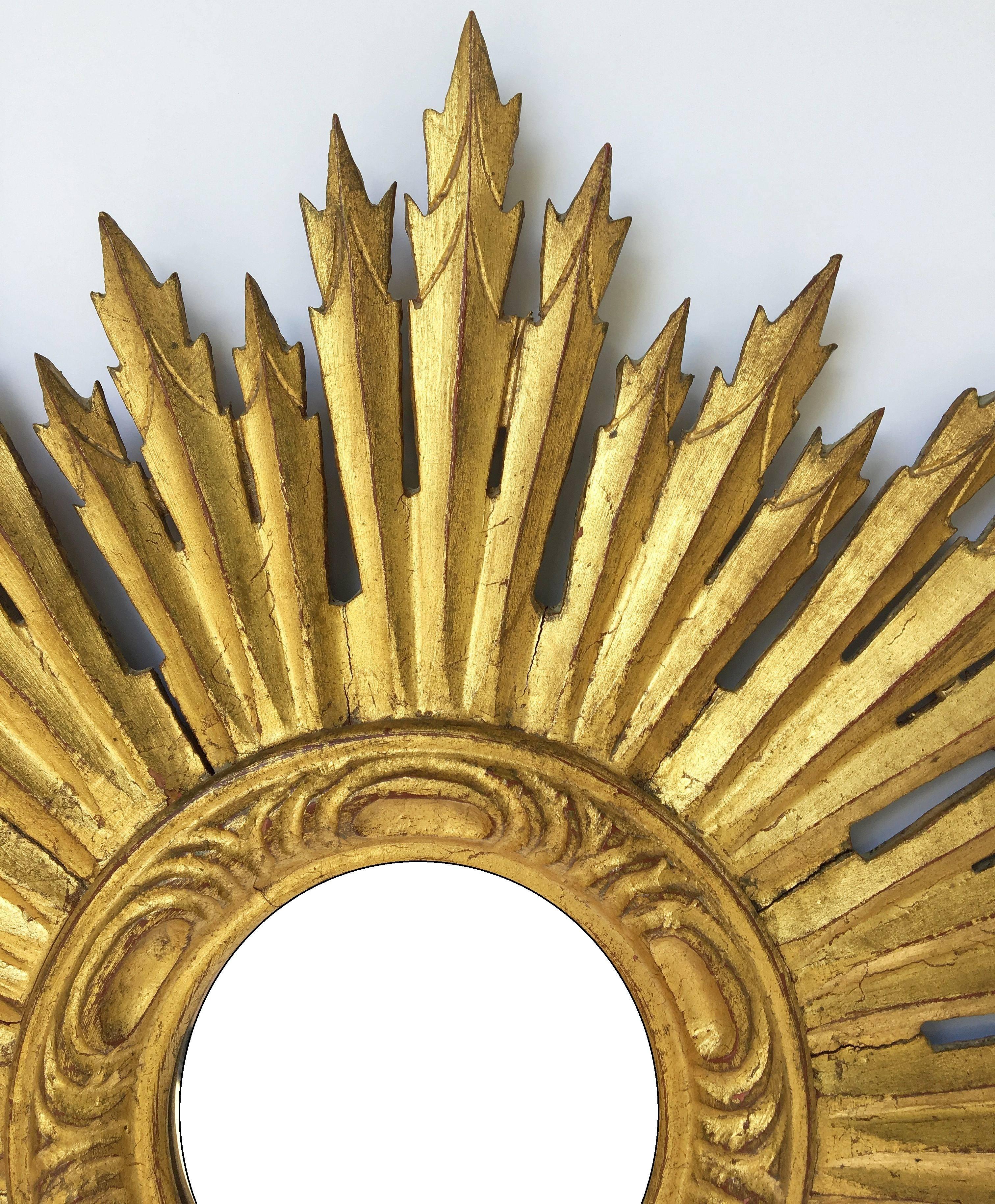 A lovely French gilt sunburst (or starburst) mirror, 24 inches diameter, with mirrored glass center in moulded frame.