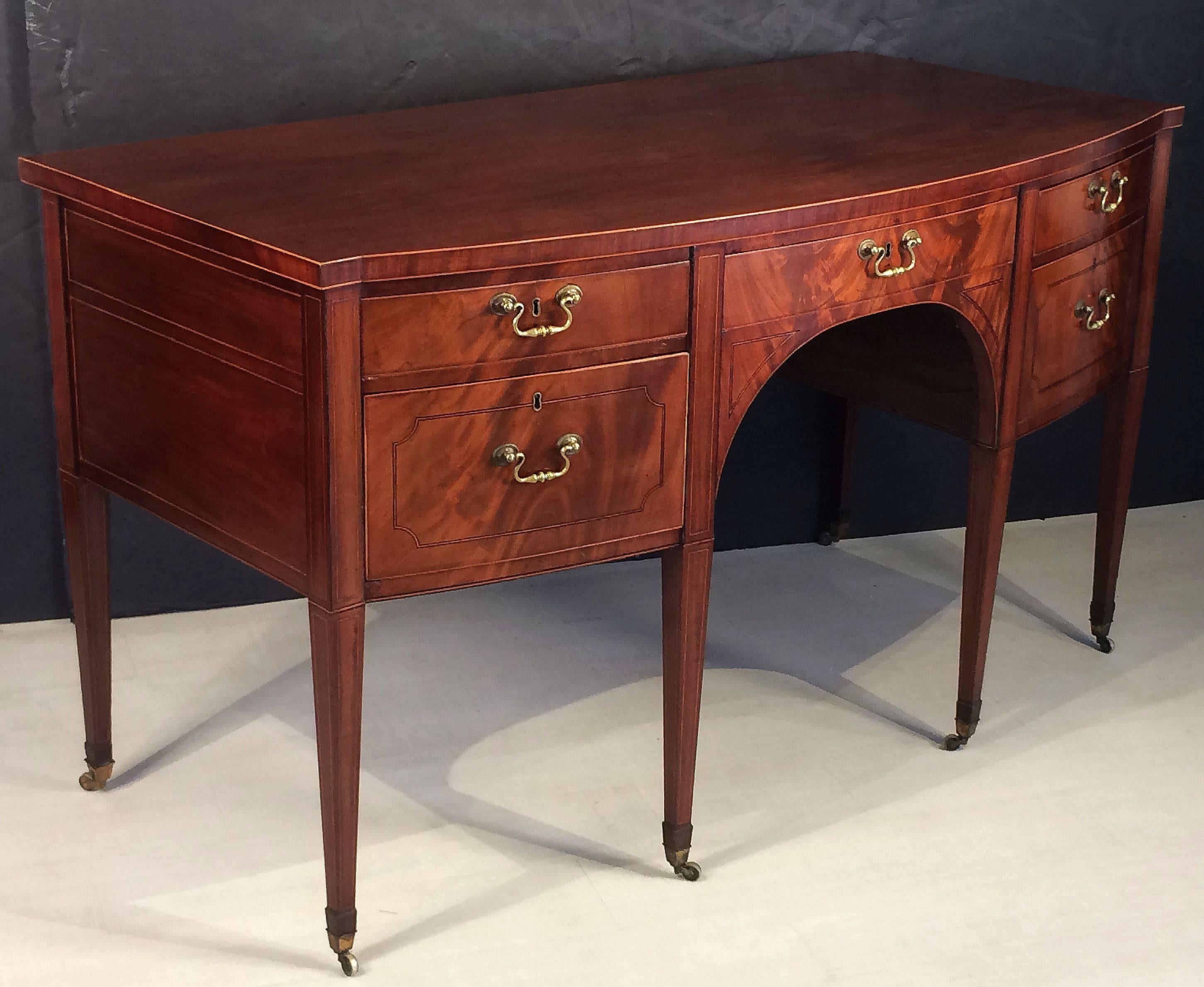 A handsome English sideboard server (or serving console) from the Regency period, featuring a bowed moulded top, over an inlaid flame mahogany frieze with two left-facing cabinet drawers, bowed middle large drawer, and two right-facing cabinet
