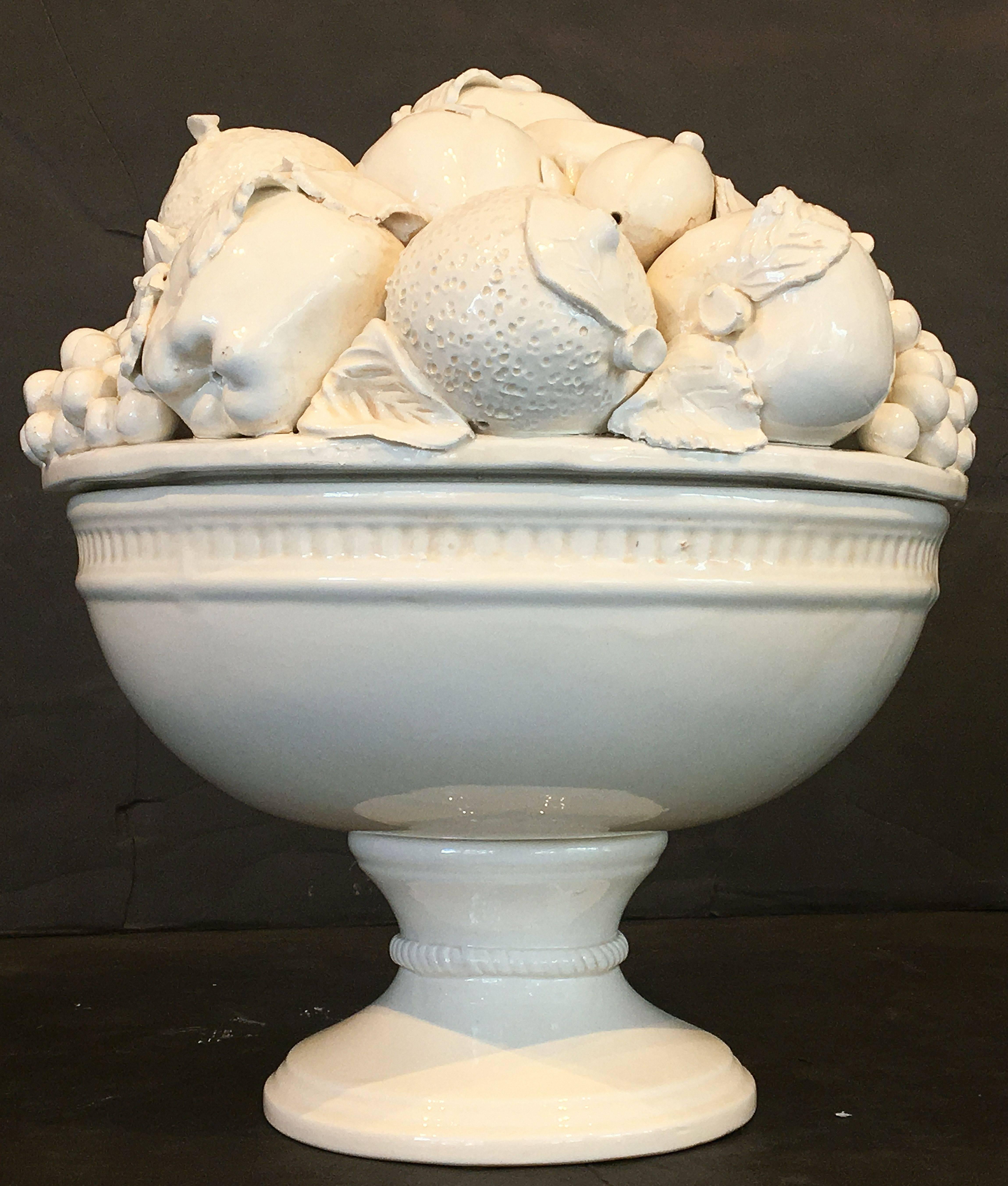 A fine large Italian creamware or white glazed ceramic pedestal bowl of fruit, featuring a fitted lid with a relief of fruit including apples, grapes, and pomegranates over a round raised pedestal bowl base. 

Great for serving or for use as a