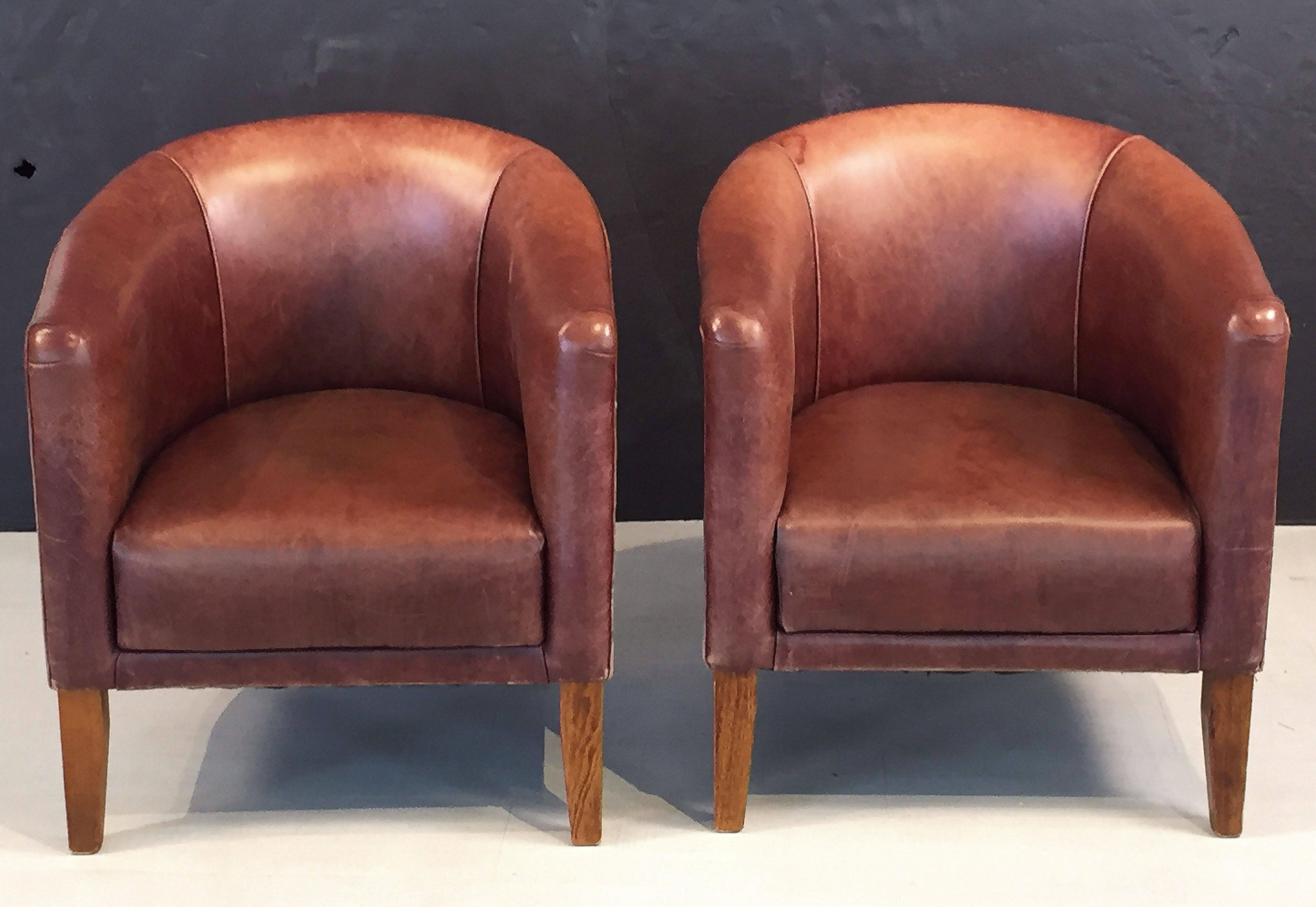 A fine pair of Italian leather lounge or club chairs, each chair featuring a comfortable upholstered seat and back with a barrel-style design, set upon four legs.

Priced individually - $3895 each chair.