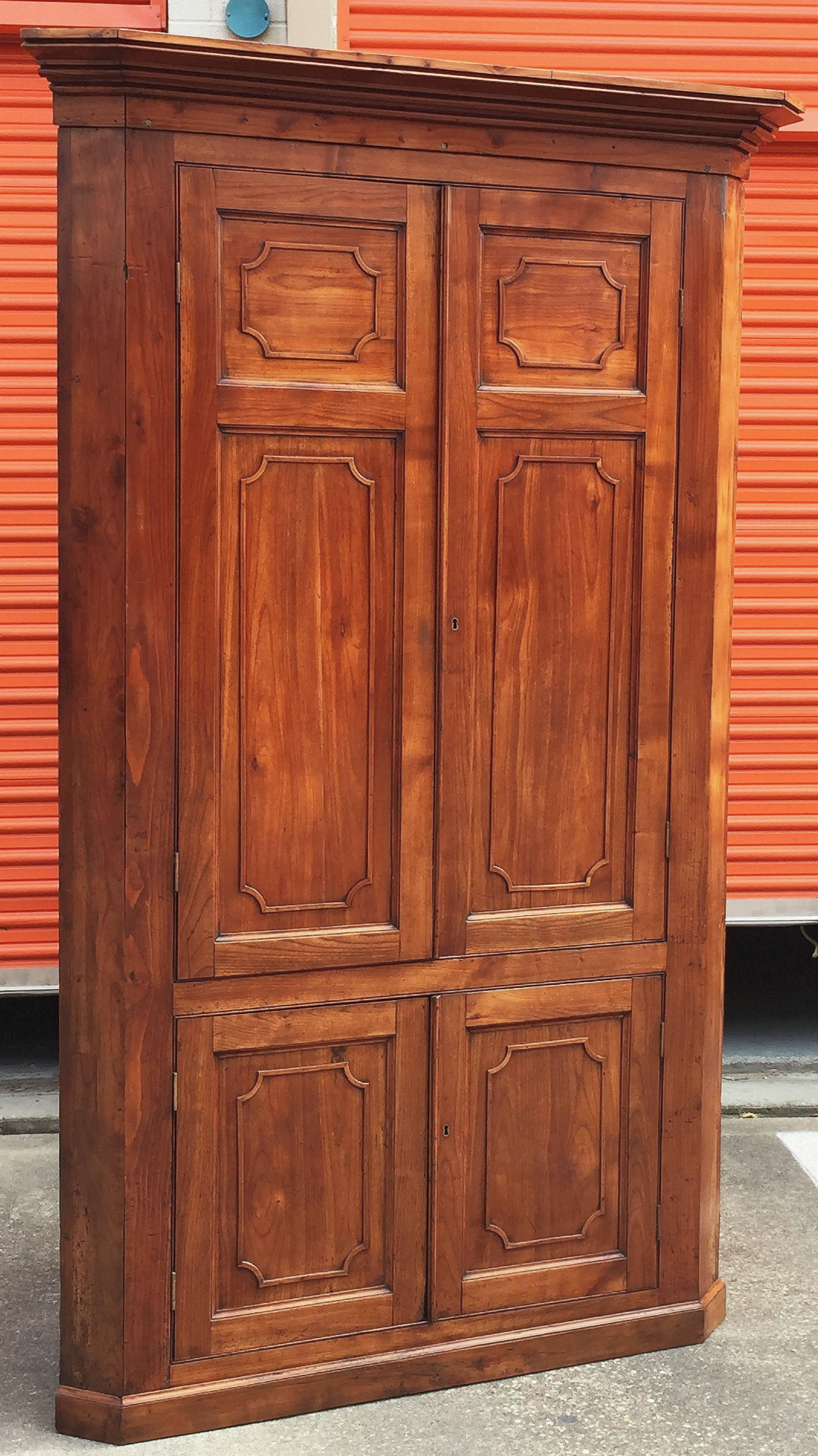 Ein feiner französischer zweistöckiger Eckschrank oder Schrank aus Kirschholz, mit Kronenleiste über einer gekanteten Front der oberen Etage, mit zwei getäfelten Türen, die einen Innenraum mit Regalen umschließen, die gekantete untere Etage mit zwei