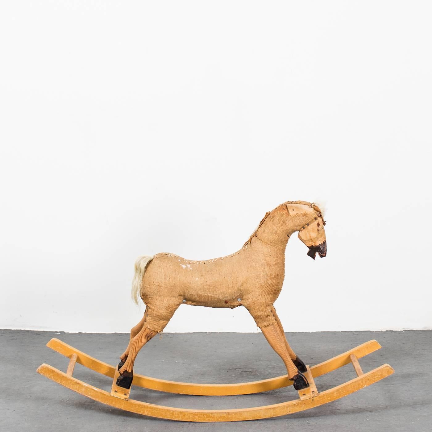 A rocking horse made during the 20th century in Sweden. Upholstered in jute with painted details standing on a wooden frame.