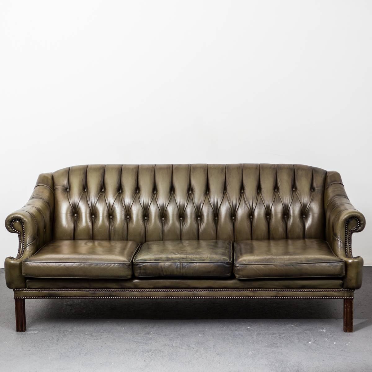 A green leather sofa made in England, circa 1950. Leather in beautiful condition decorated with nailheads. All upholstered back.