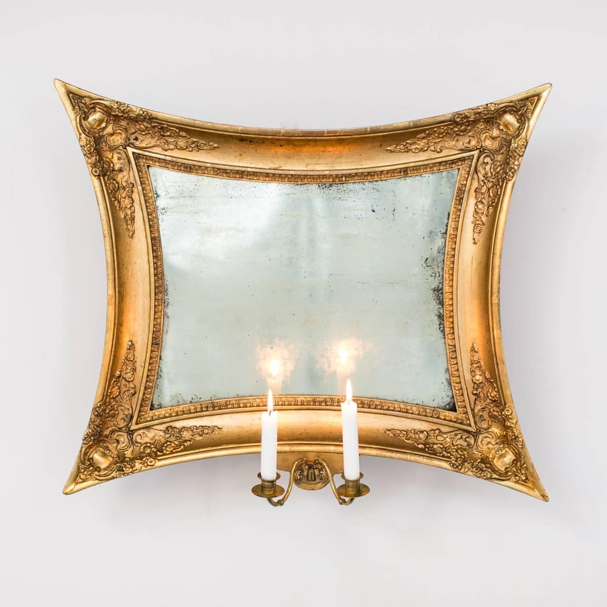 Mirrored wall sconce in a gilded frame with two arms for candles. Made during the later part of the Empire period, circa 1830.