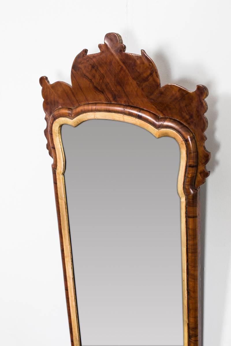 A gorgeous mirror made in England during the Queen Anne period, early 18th Century. A curved frame of walnut with a gilded inner lining. 