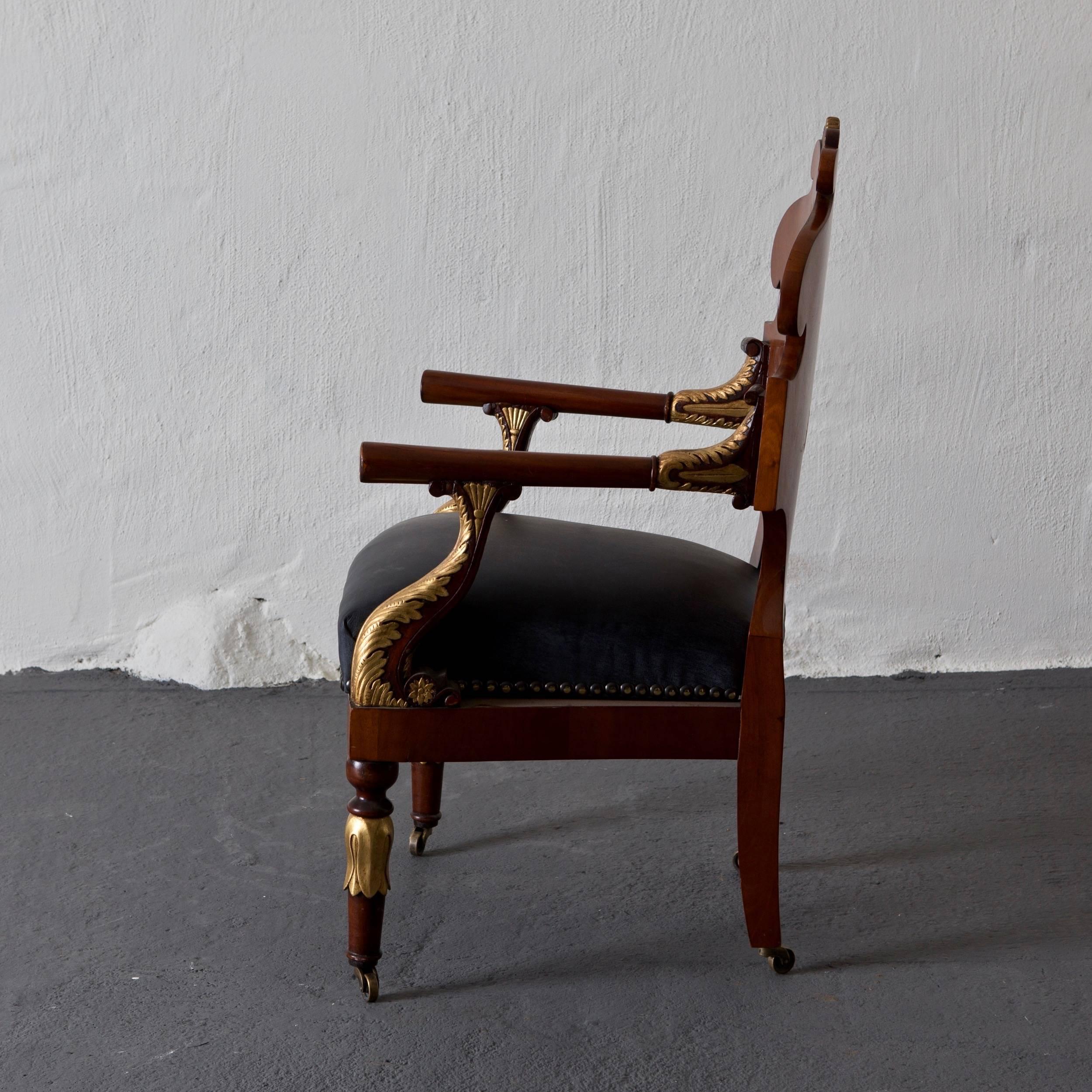 Chair made during the 18th century and Empire period in Russia. Frame made from dark mahogany with gilded details. Seat upholstered in black leather with antiqued nail heads. Leaf carved legs in casters. 

         